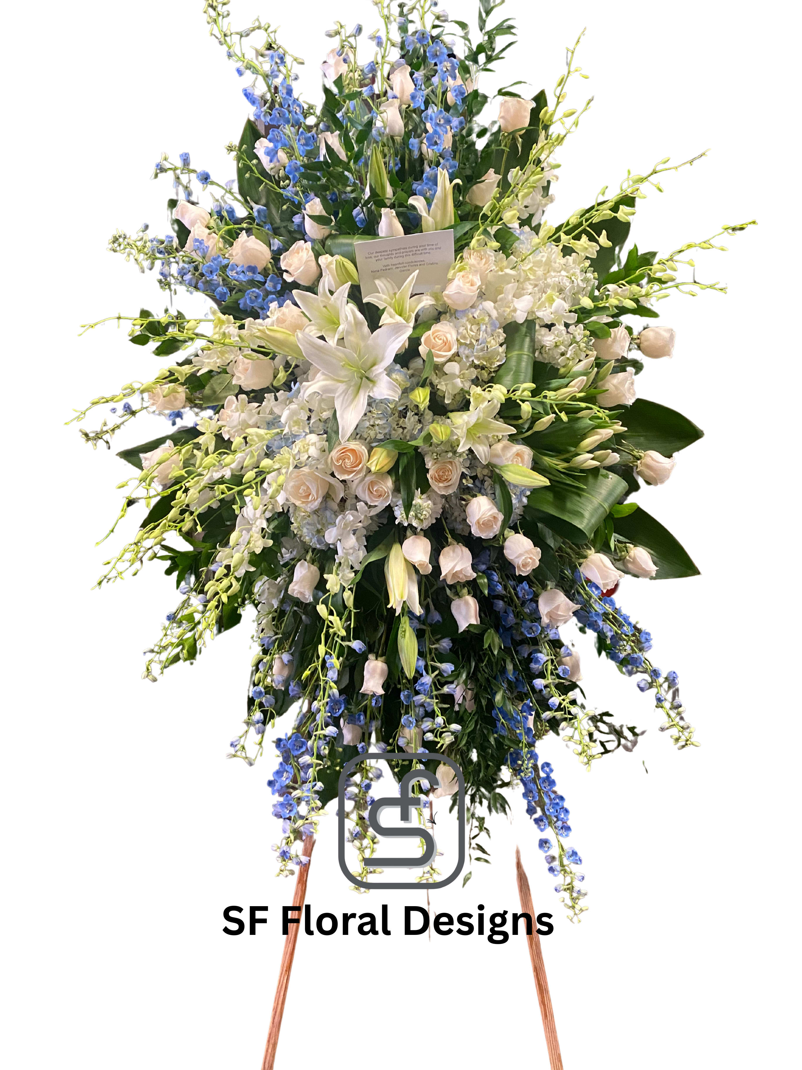 Tall standing spray of white lilies, cream roses, and blue delphinium on a wooden easel