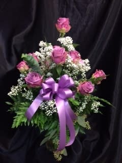 Pink rose bouquet with white filler flowers and a purple ribbon