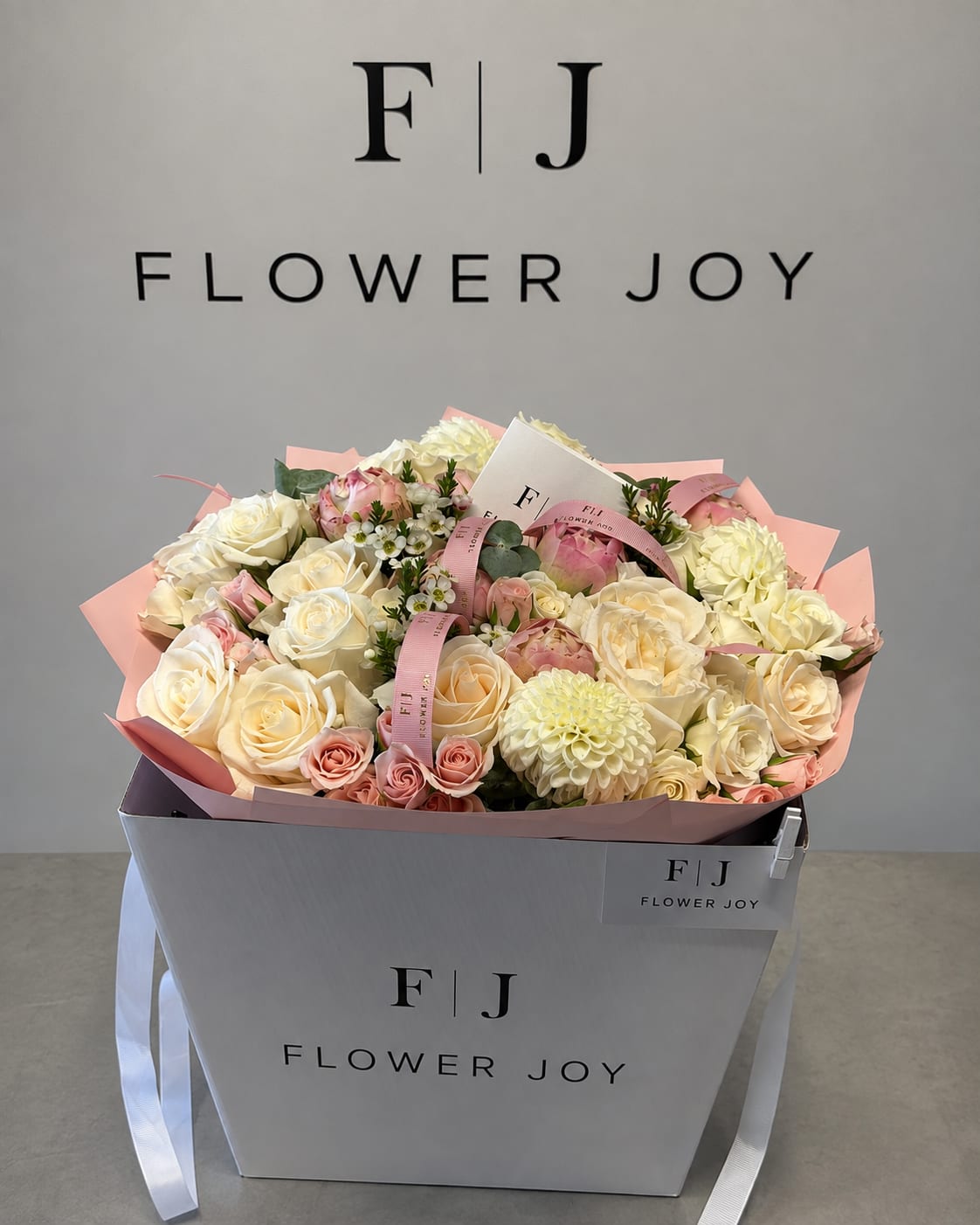 Bouquet of cream and blush roses with pale dahlias in a gift box