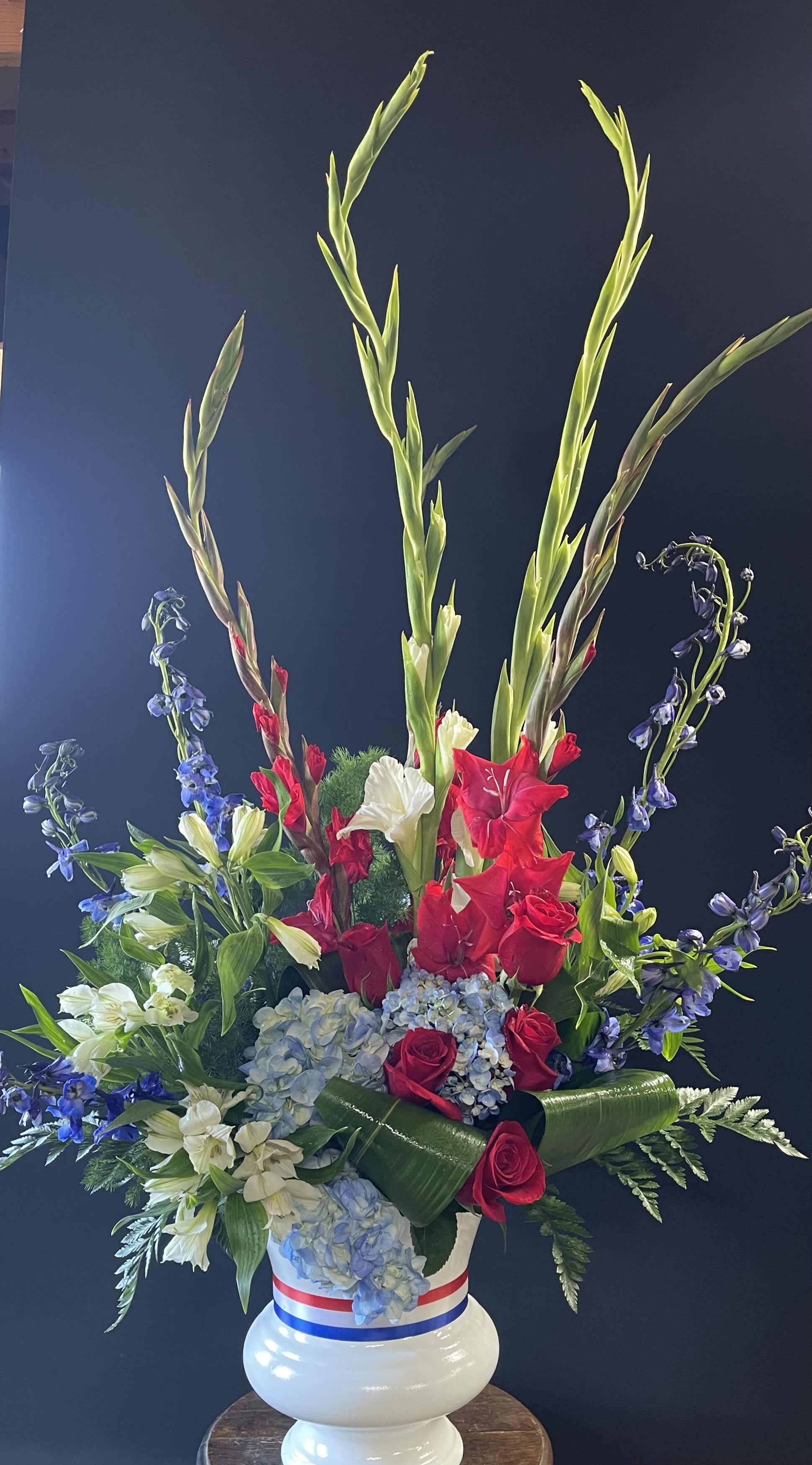 Tall red, white, and blue floral arrangement in a white vase