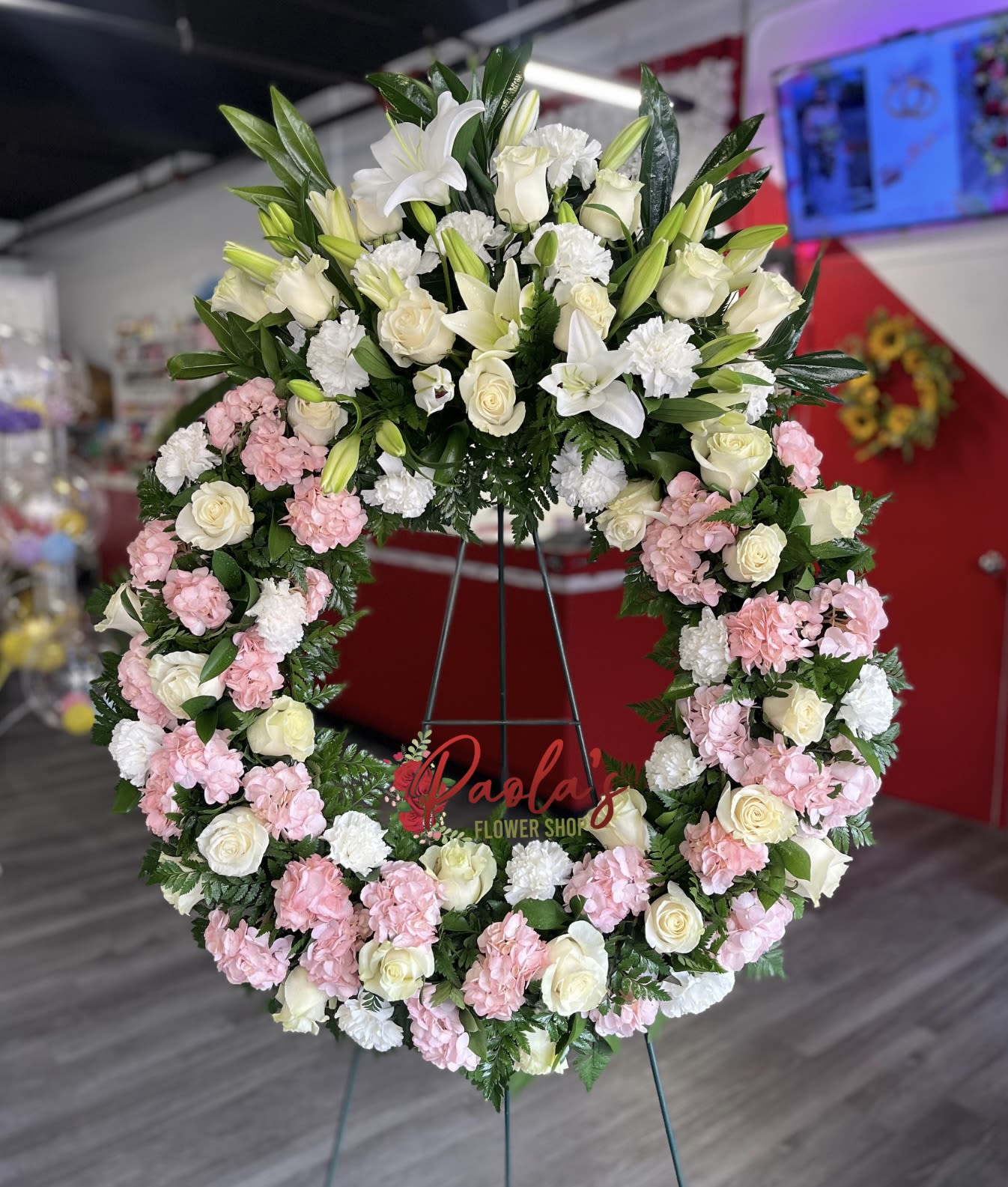 Large floral wreath with white lilies, roses, and pink carnations