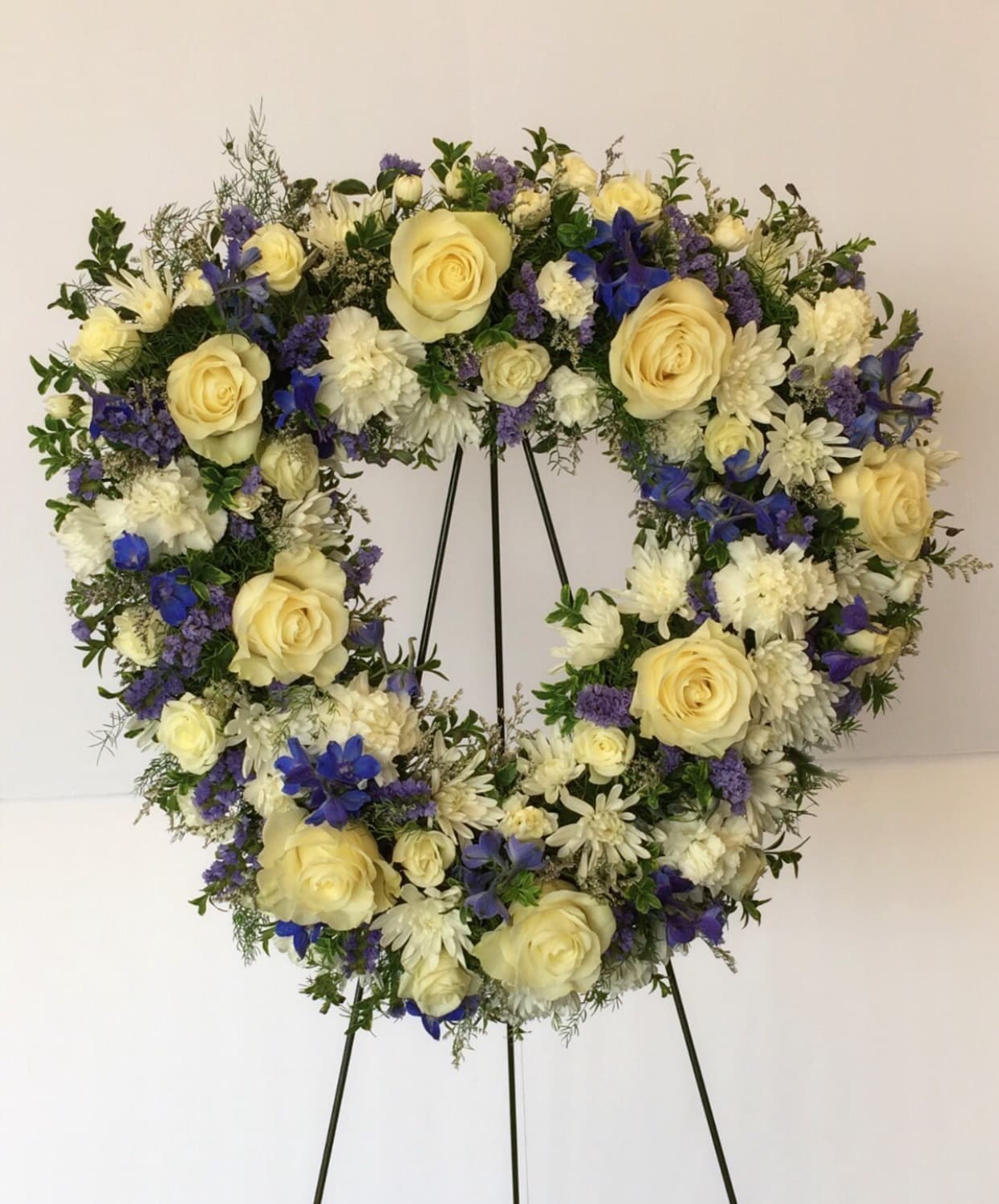 Heart-shaped floral wreath with cream roses, white blooms, and blue flowers