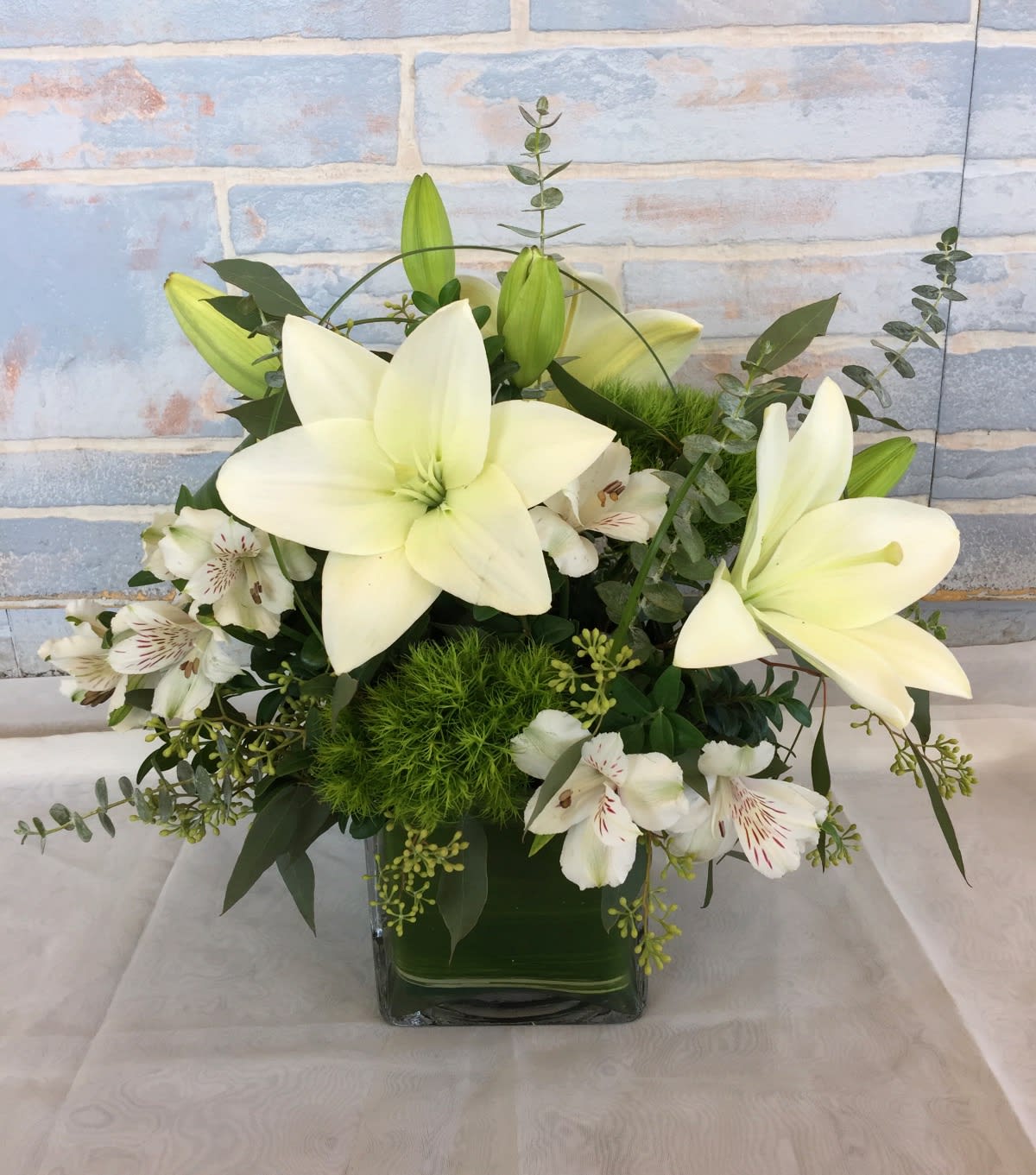 White lilies and white alstroemeria in a square glass vase