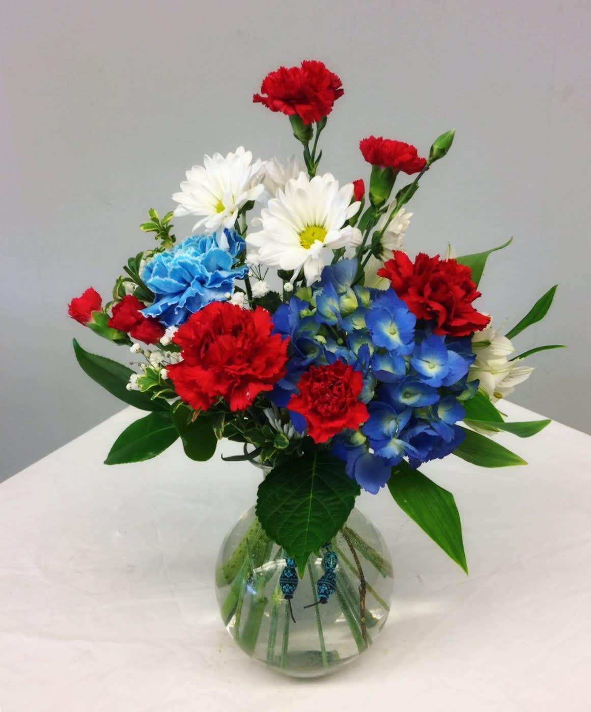 Colorful bouquet of carnations and daisies in a round glass vase