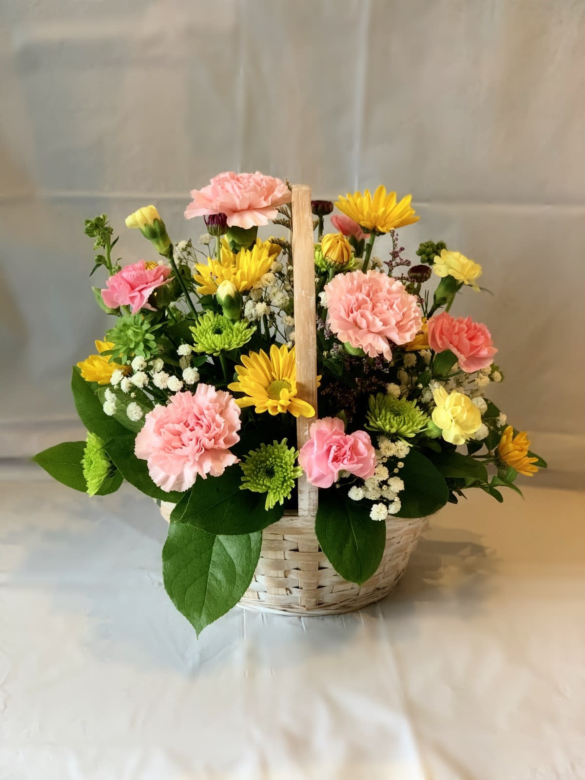 Basket arrangement of pink carnations and yellow daisies