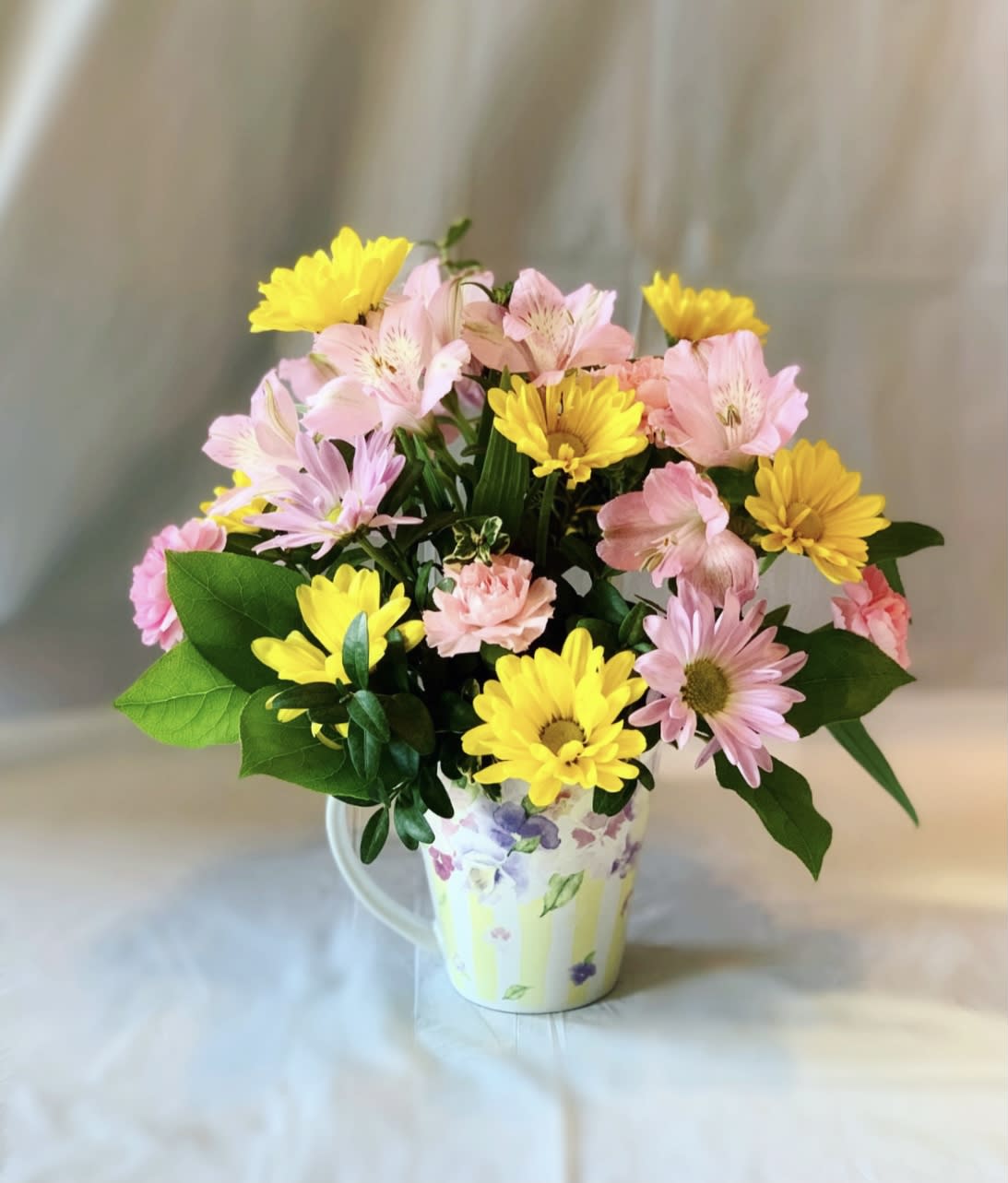 Pink and yellow flowers arranged in a floral mug