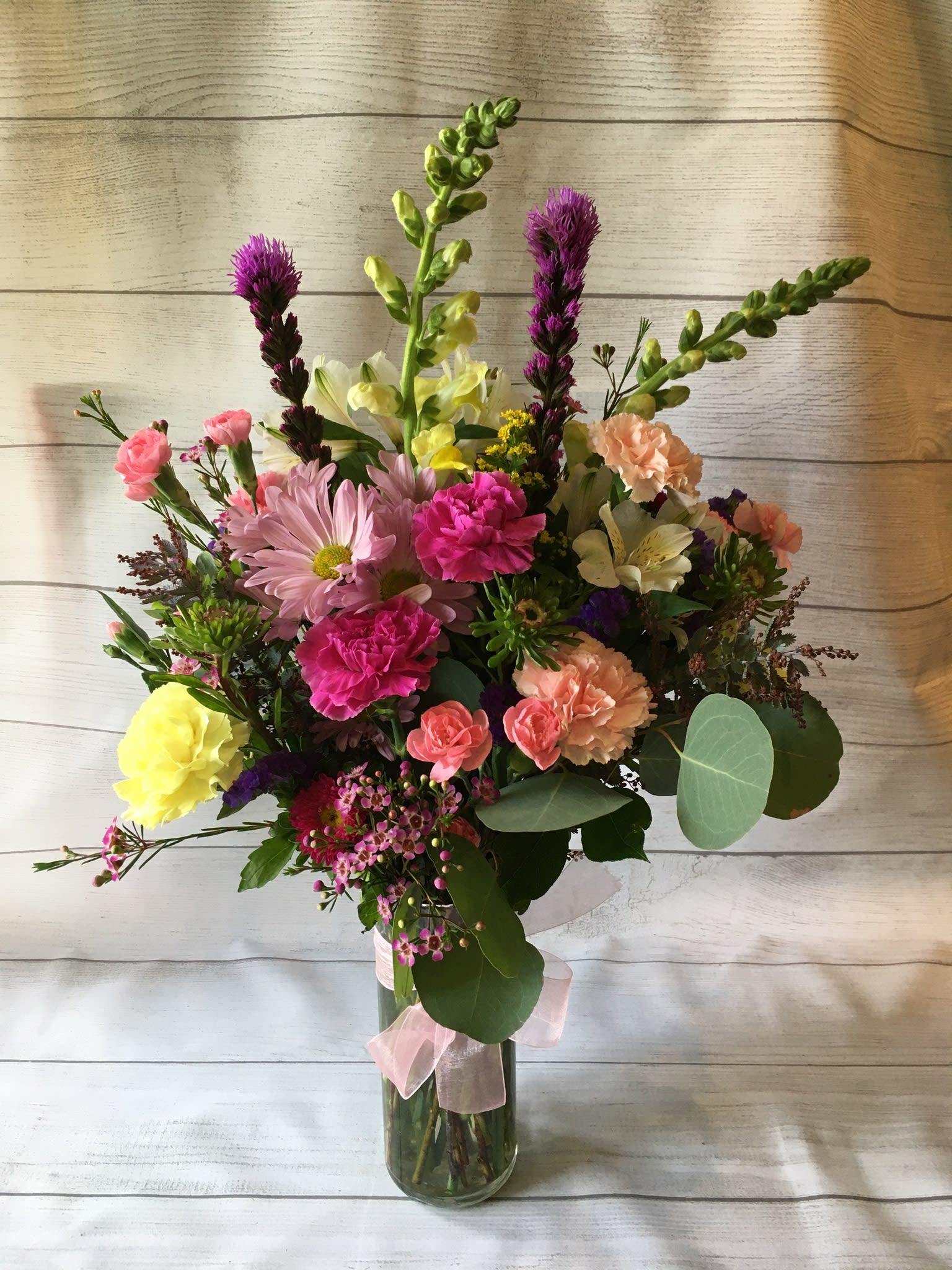 Mixed bouquet in a glass vase with pink, yellow, and peach flowers