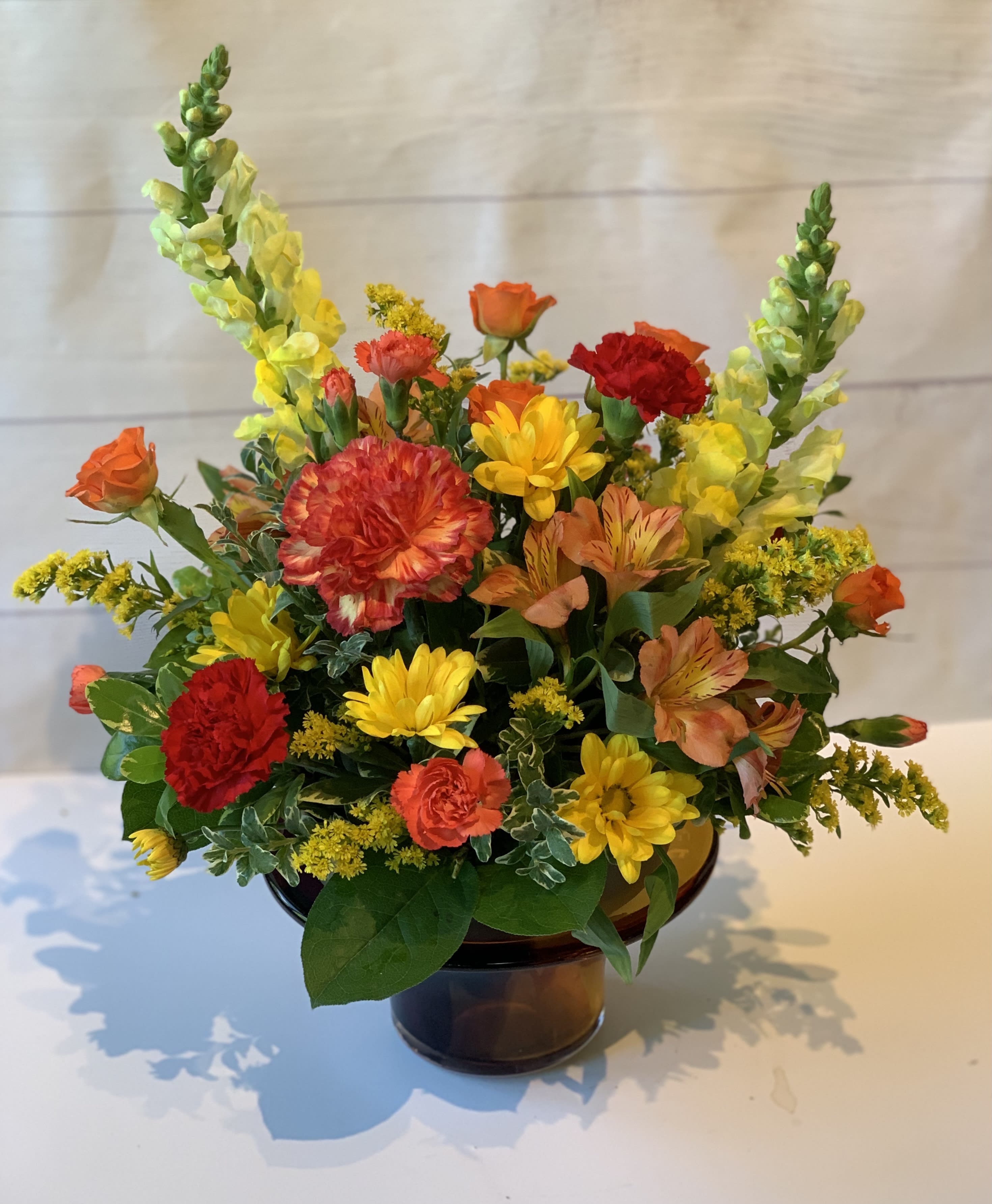 Colorful mixed flower arrangement in a brown glass vase