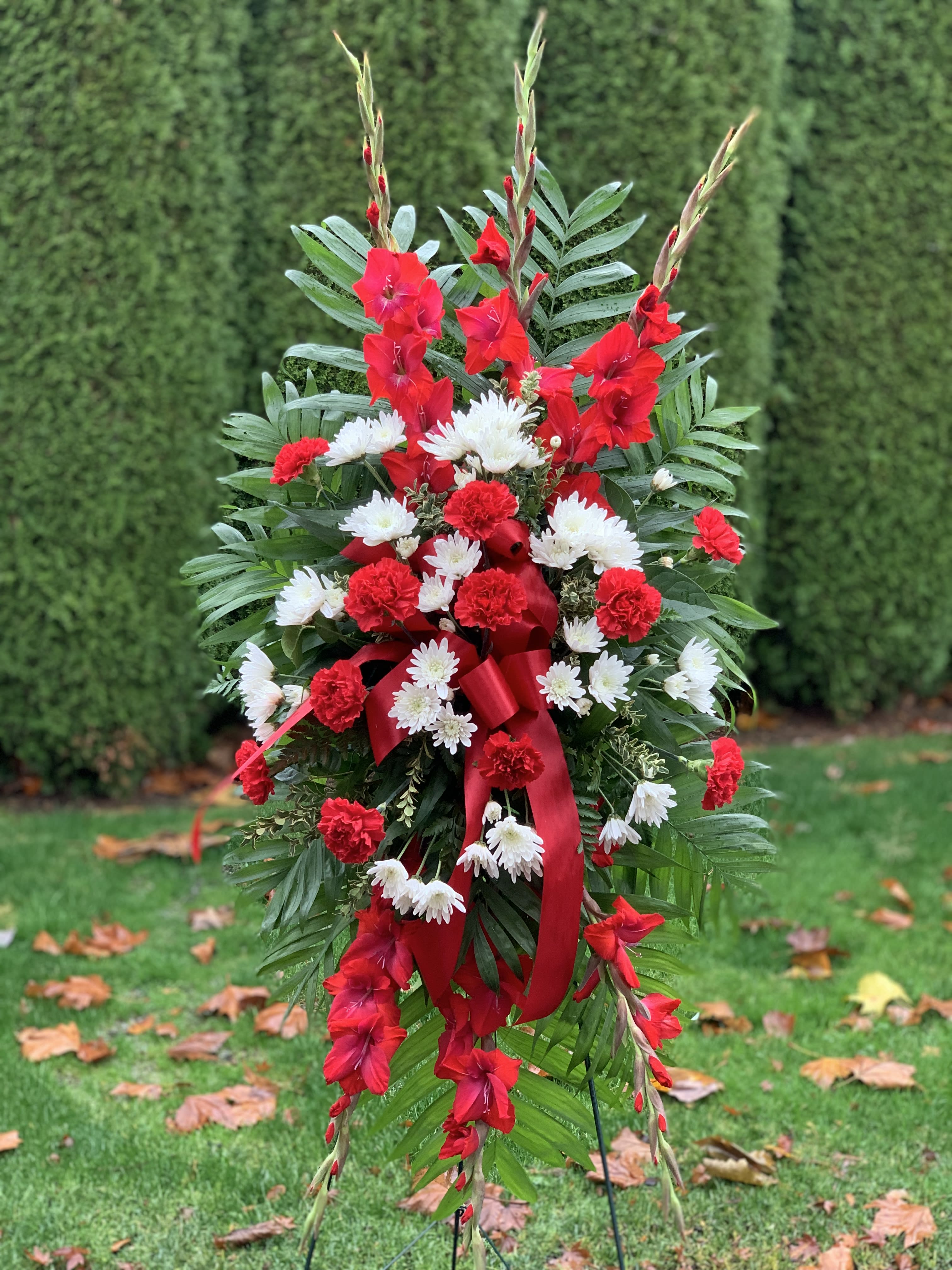 Standing red and white floral spray with ribbon on a wire easel