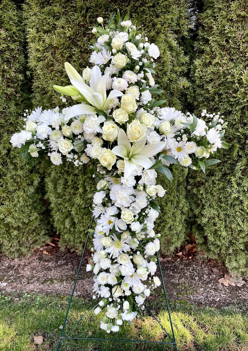 White floral cross standing on a metal easel