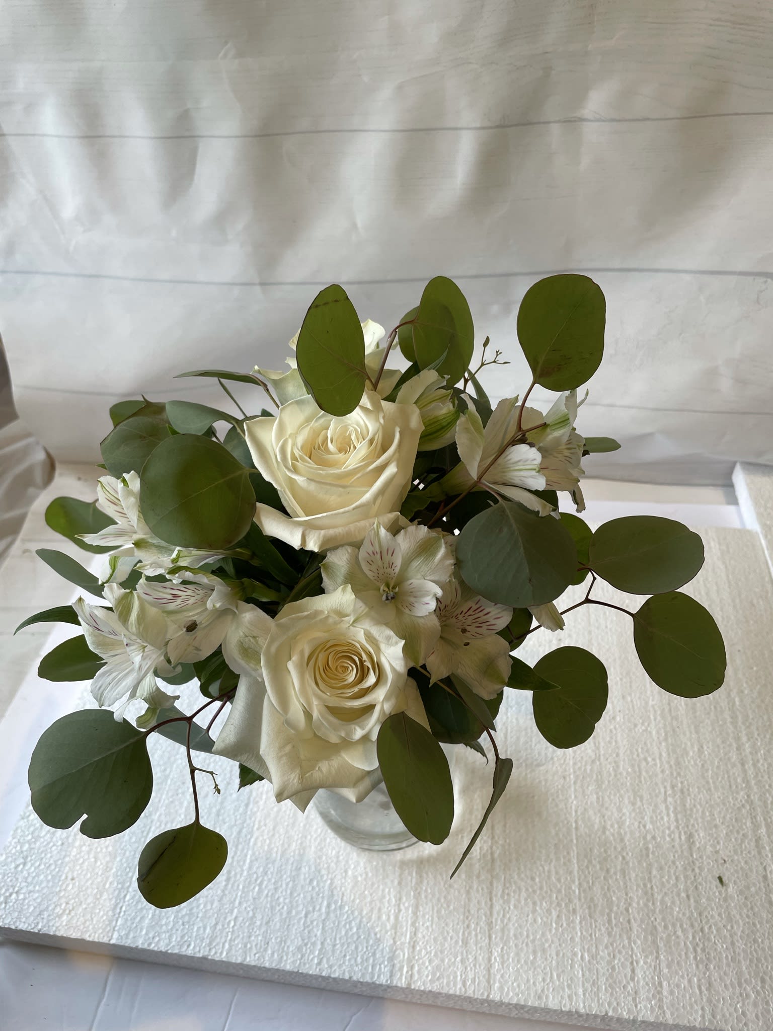 White rose bouquet with white alstroemeria in a clear vase