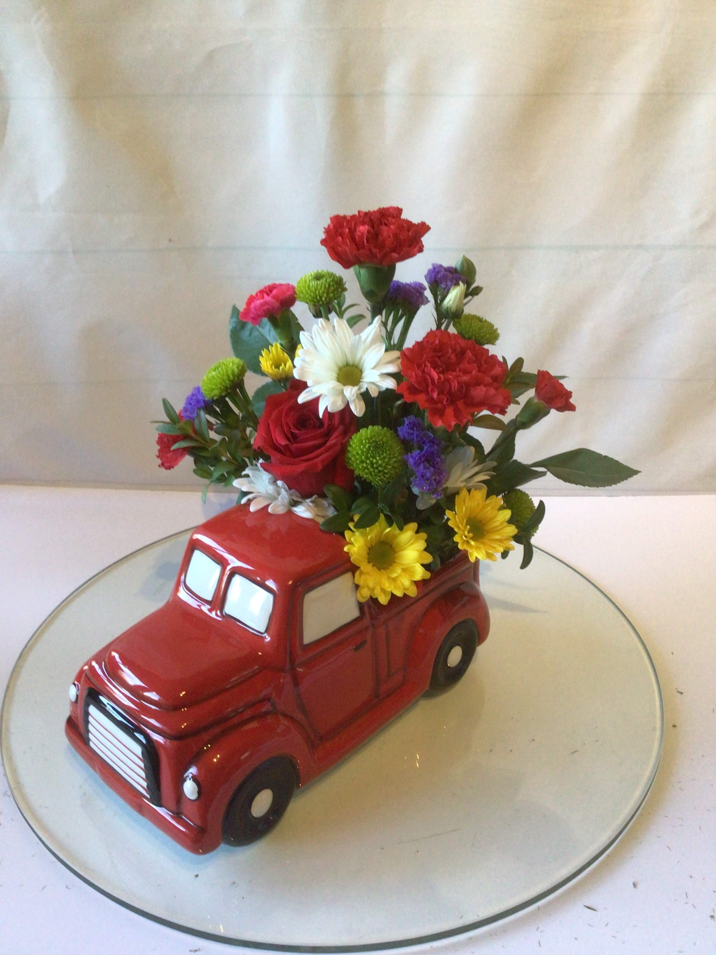 Flowers arranged in a red ceramic truck planter