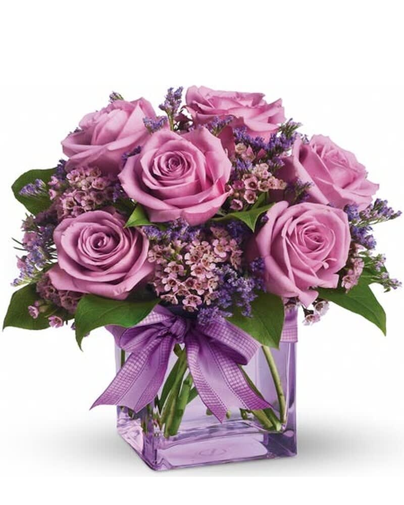 Pink roses in a purple glass vase with a ribbon bow