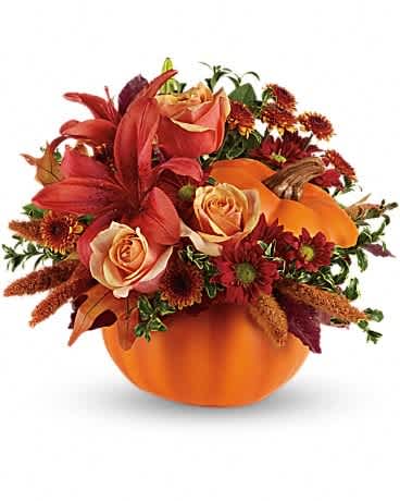 Autumn floral arrangement in an orange pumpkin container with roses and lilies