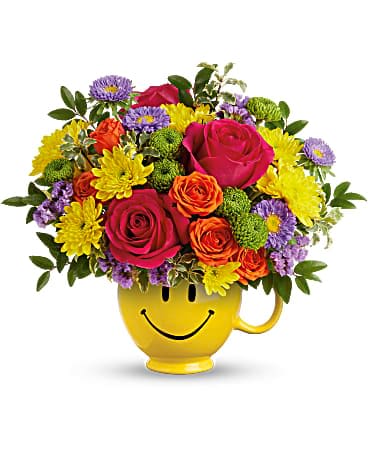 Teleflora's Choose Happy Bouquet - Smile, you've got flowersâ¦and a mug! Brighten their day with a burst of colorful roses and a smiling ceramic mug. Hot pink roses, orange spray roses, lavender matsumoto asters, green button spray chrysanthemums, yellow cushion spray chrysanthemums and lavender sinuata statice are arranged with huckleberry and pitta negra. Delivered in a Be HappyÂ® Mug.