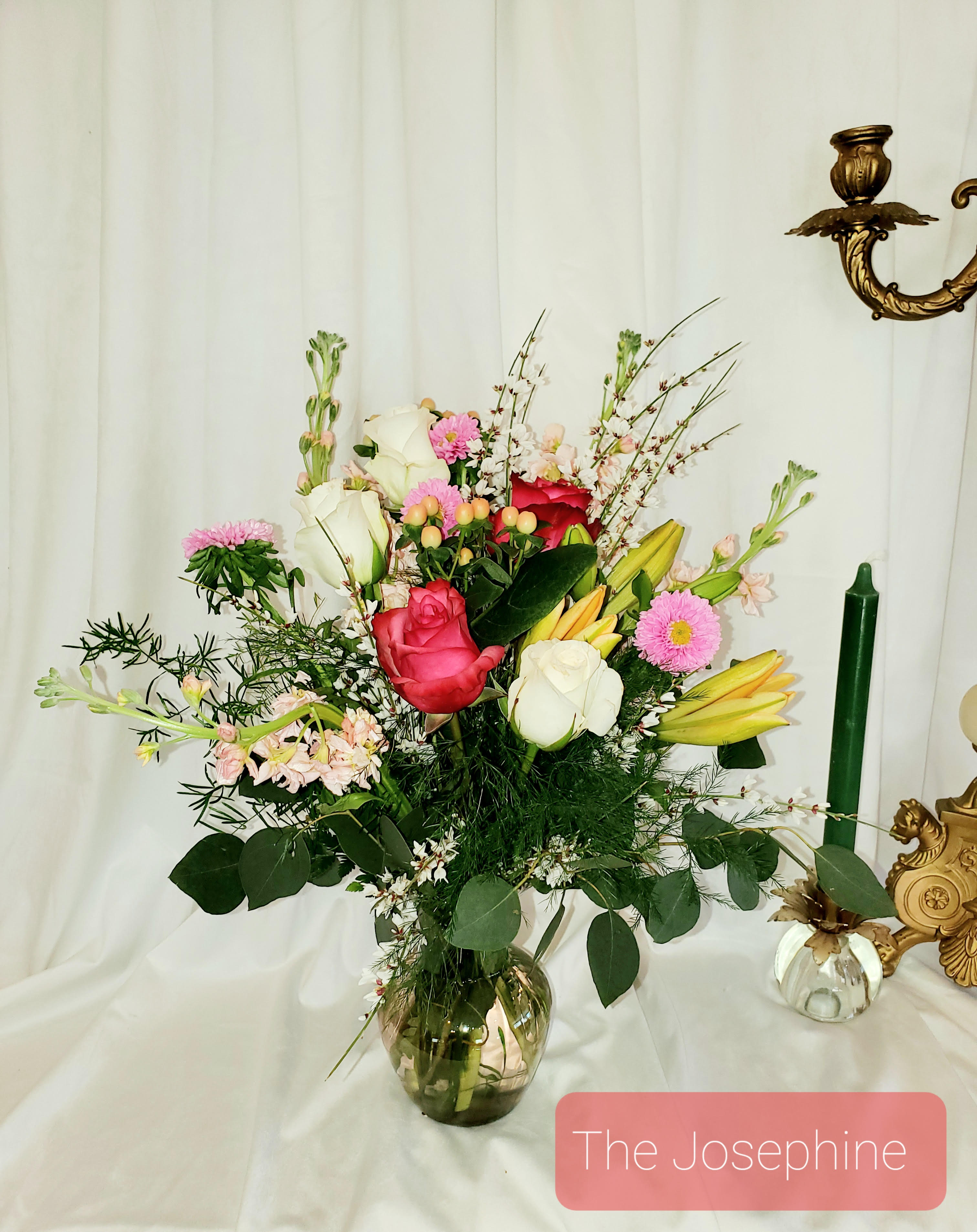 Mixed bouquet of roses, lilies, and pink daisies in a glass vase