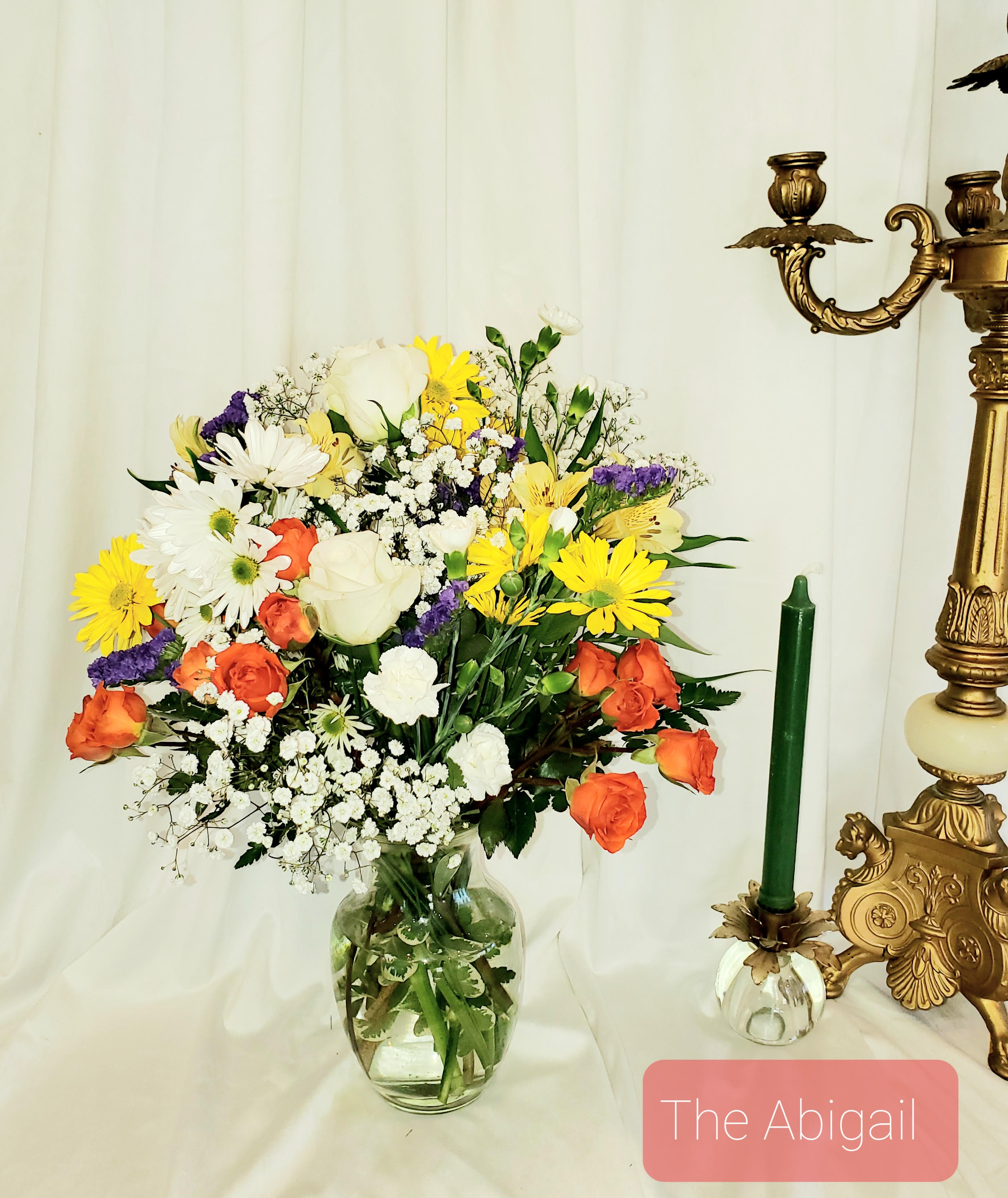 Mixed bouquet of white, yellow, orange, and purple flowers in a glass vase