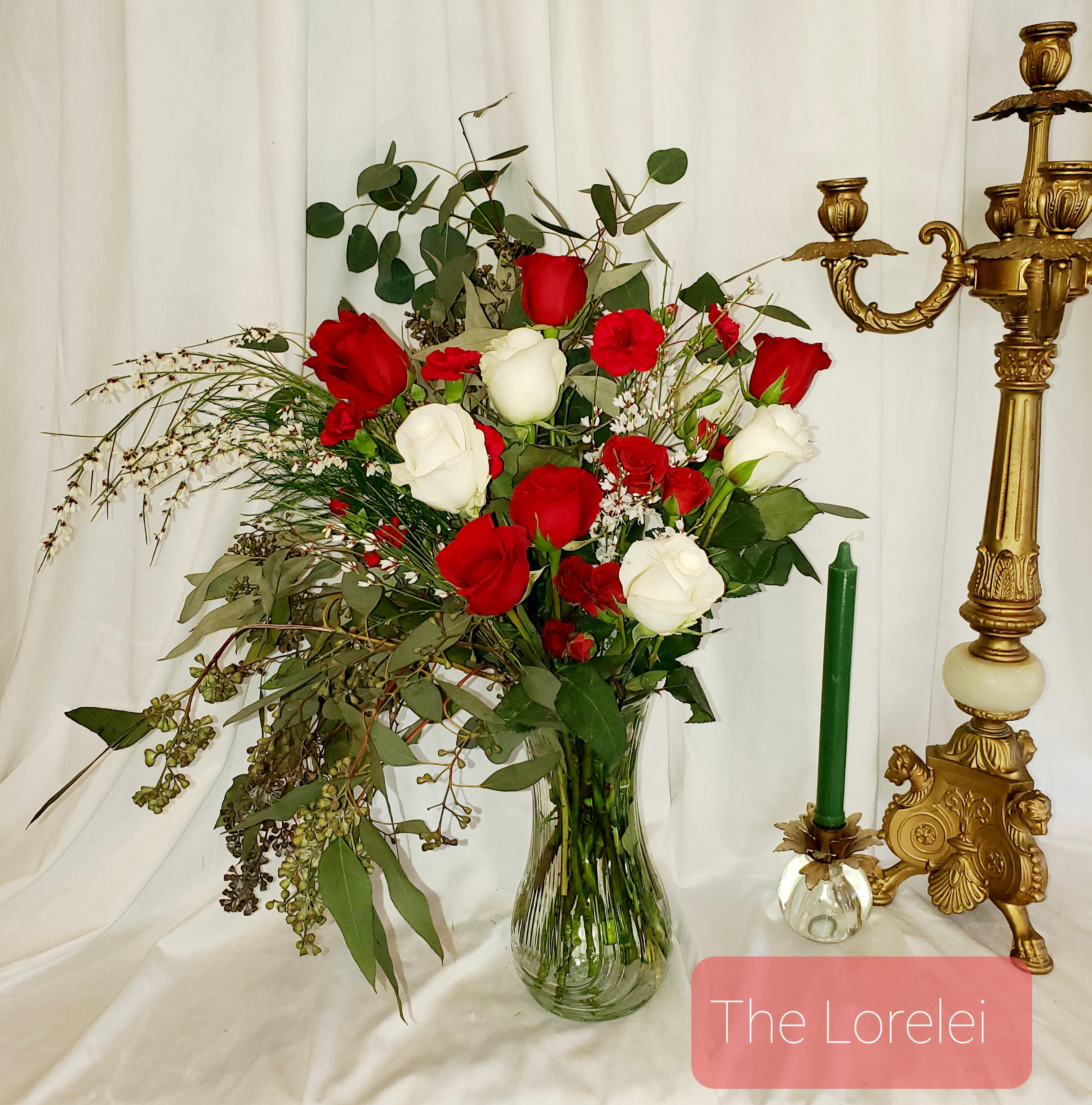 Red and white roses in a clear glass vase with greenery