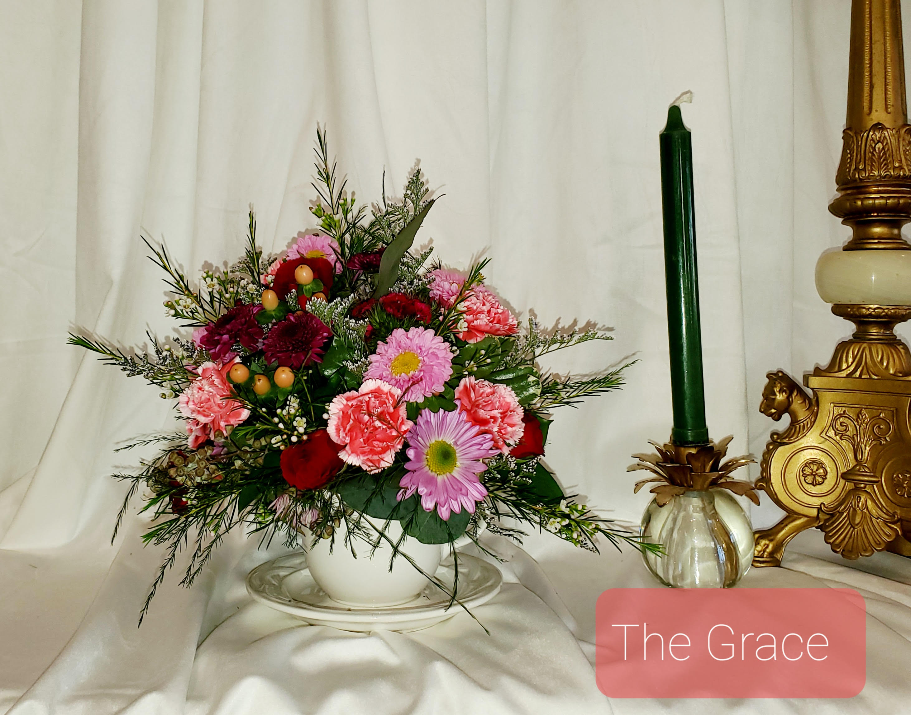 Mixed bouquet in a white bowl with a green candle beside it