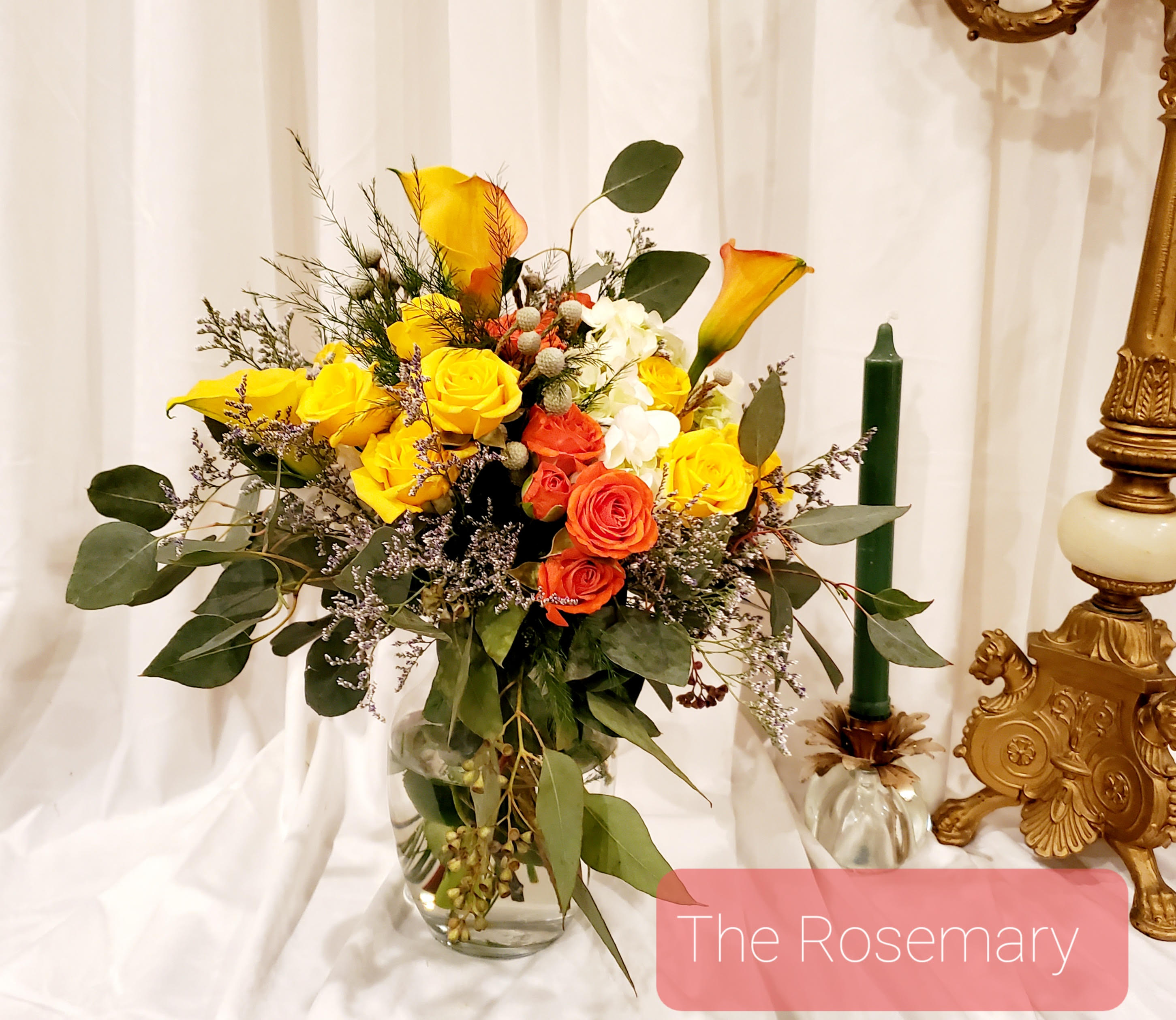 Bouquet of yellow and orange roses with calla lilies in a glass vase