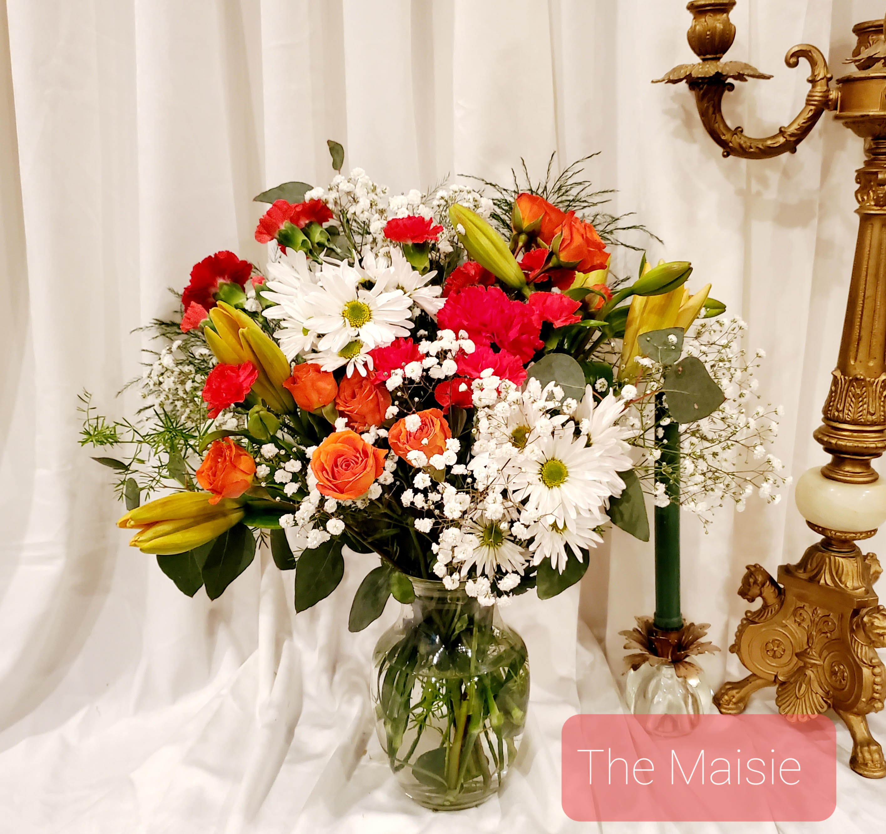 Mixed bouquet of daisies, roses, lilies, and carnations in a glass vase
