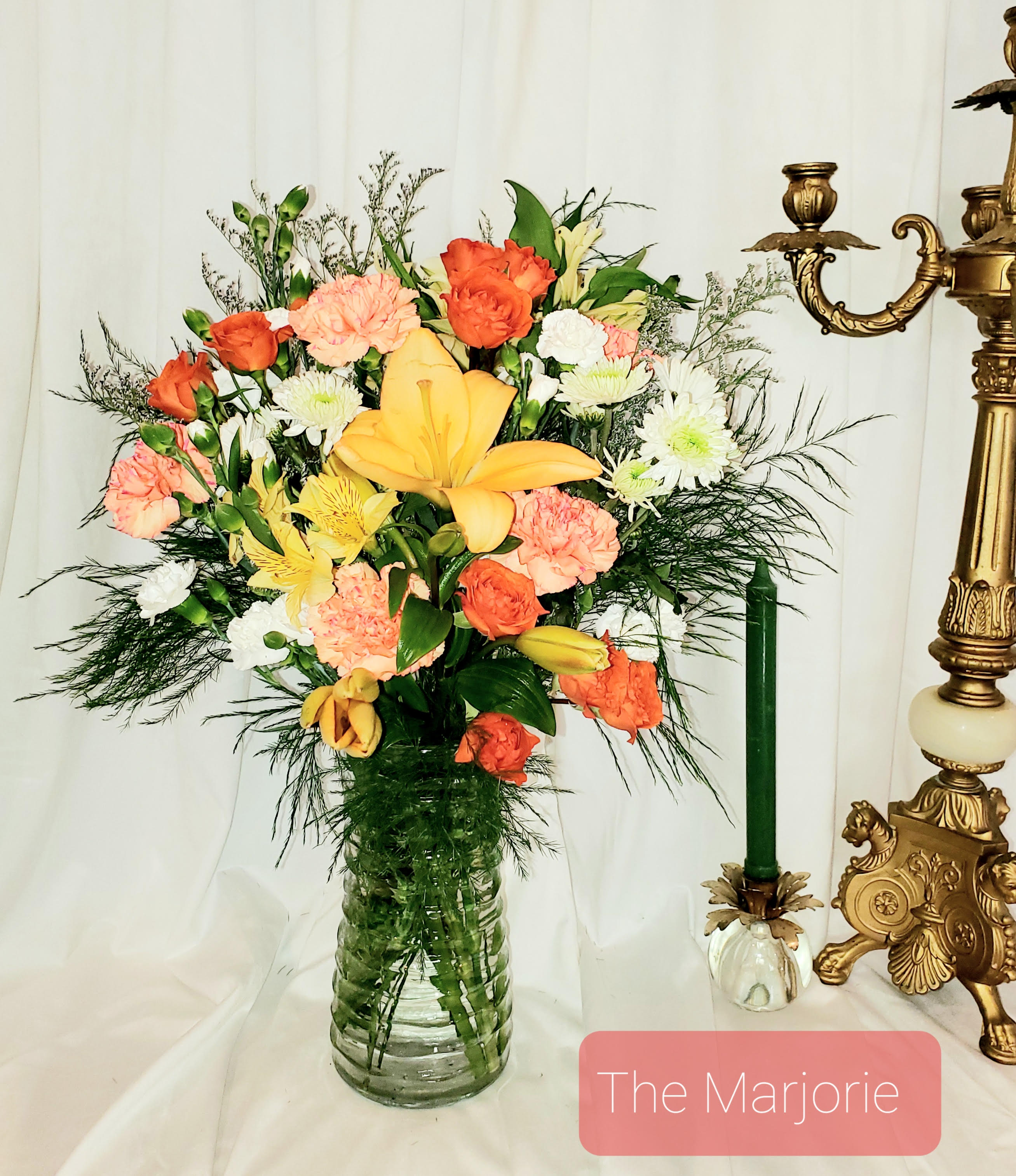 Mixed bouquet of orange, yellow, pink, and white flowers in a glass vase