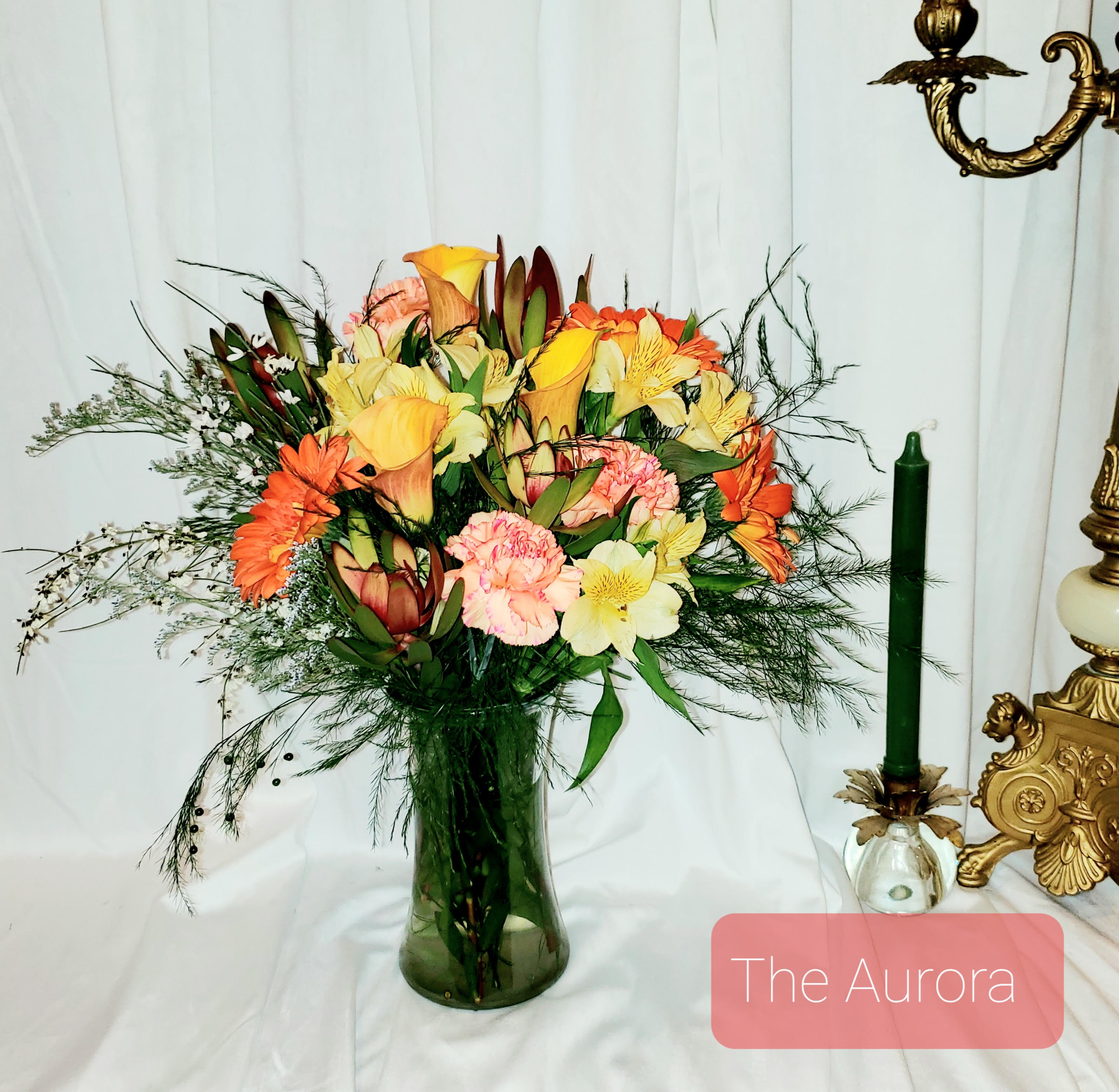 Mixed bouquet of orange, yellow, and pink flowers in a glass vase
