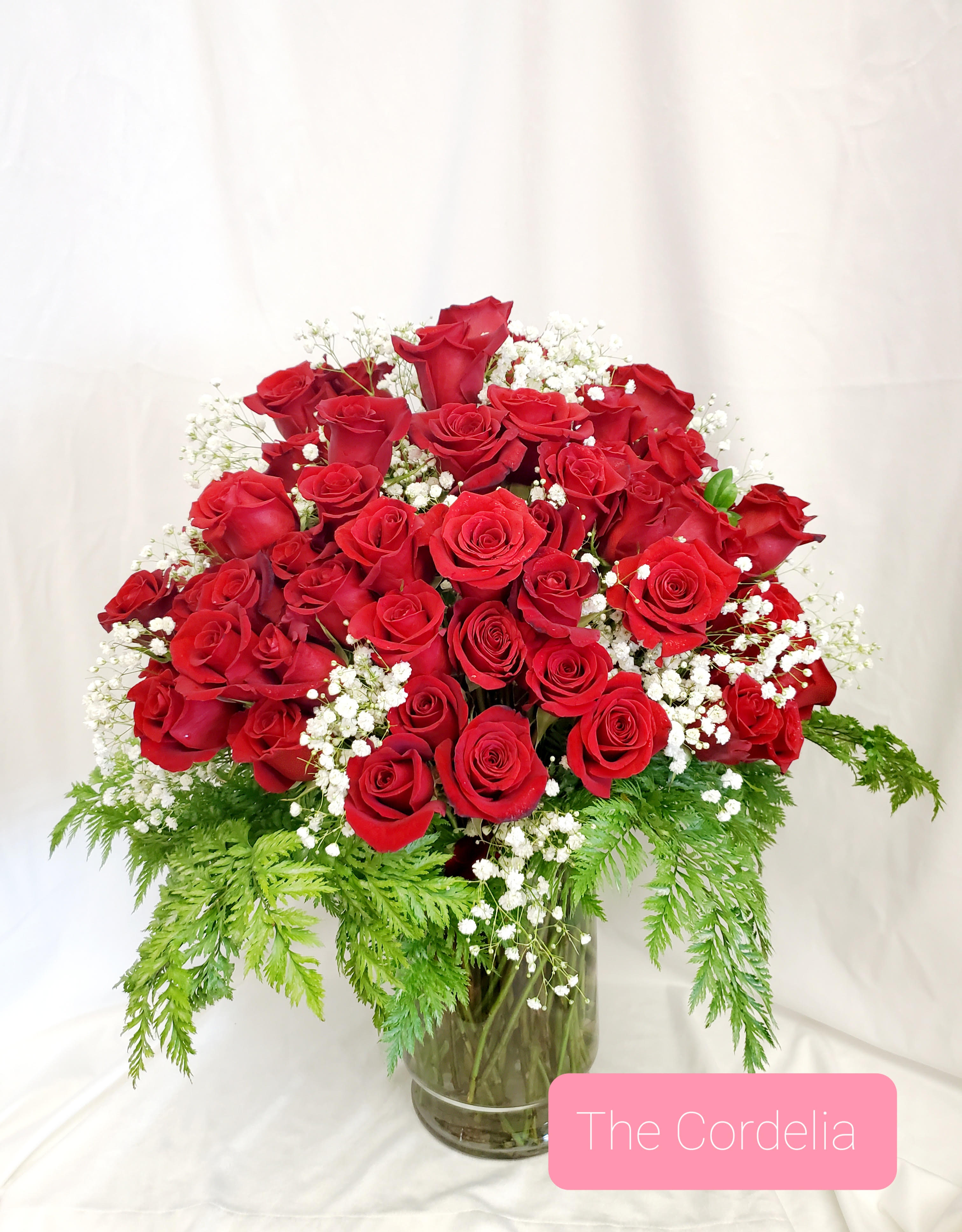 Red roses arranged in a glass vase with white baby's breath