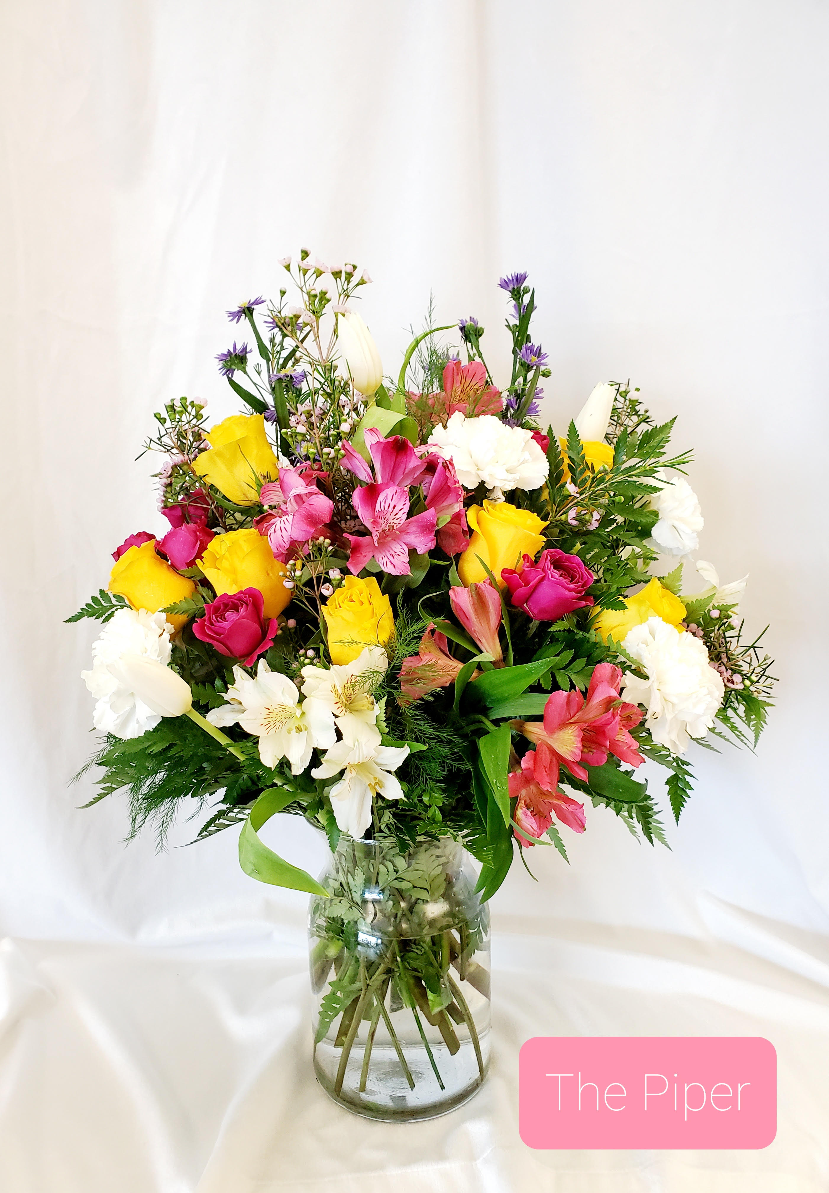 Mixed bouquet of pink, yellow, and white flowers in a glass vase
