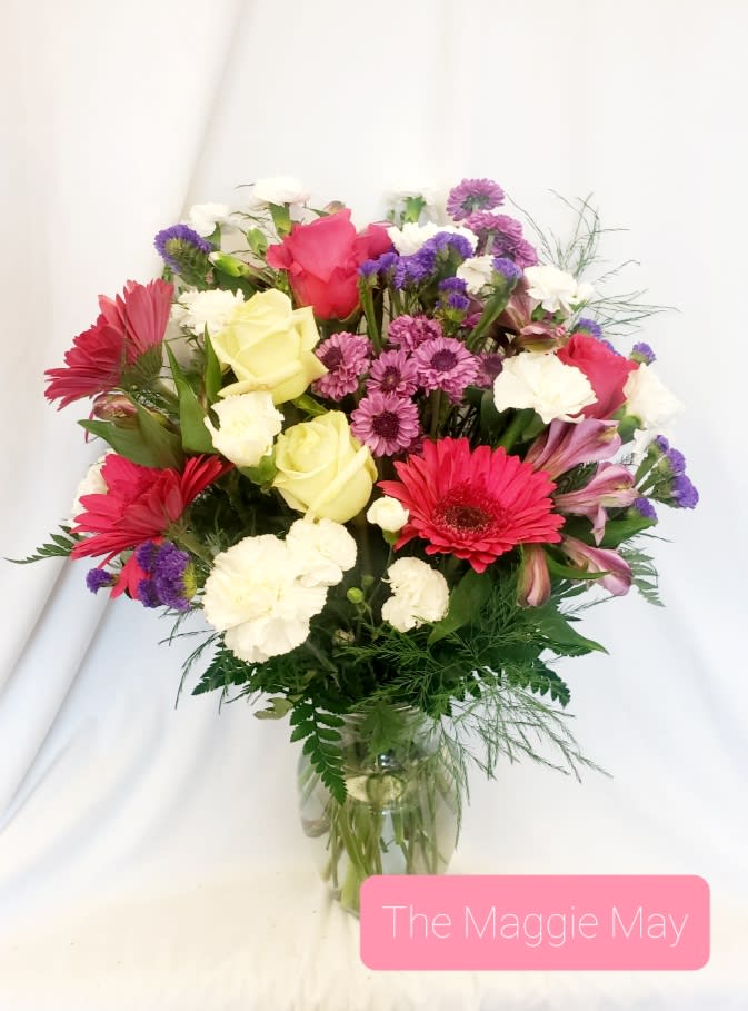 Mixed bouquet of roses, gerbera daisies, and carnations in a glass vase