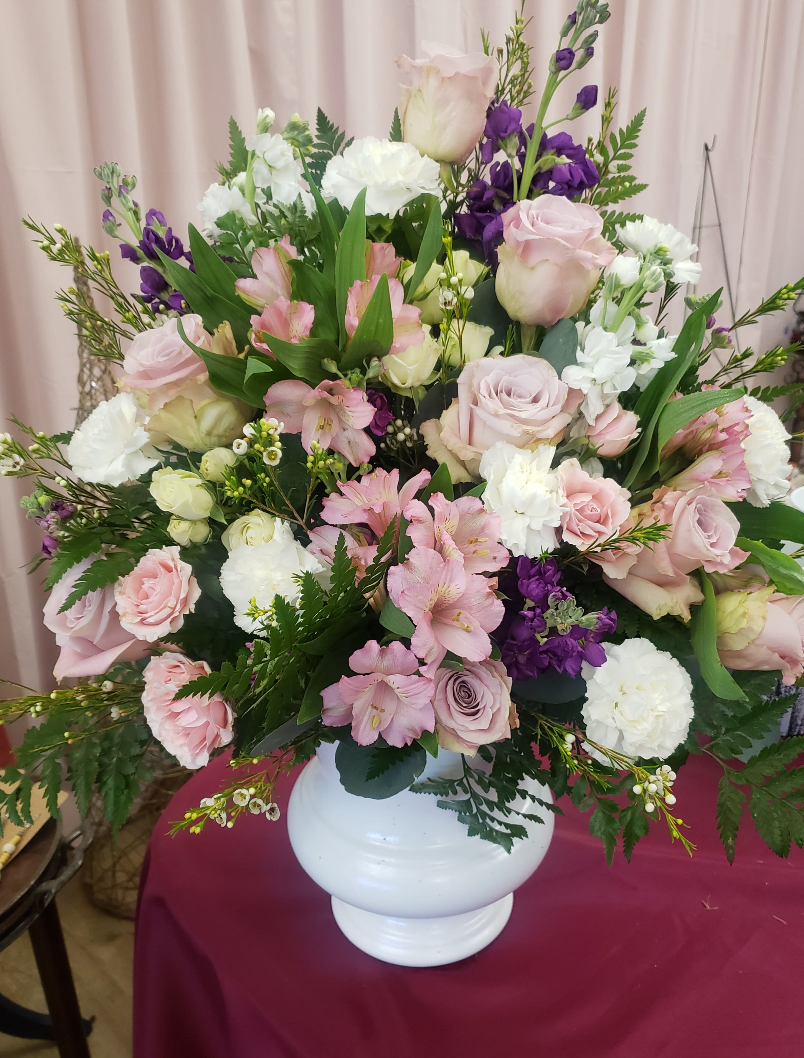 Large pastel bouquet of pink and white roses with purple flowers in a white vase