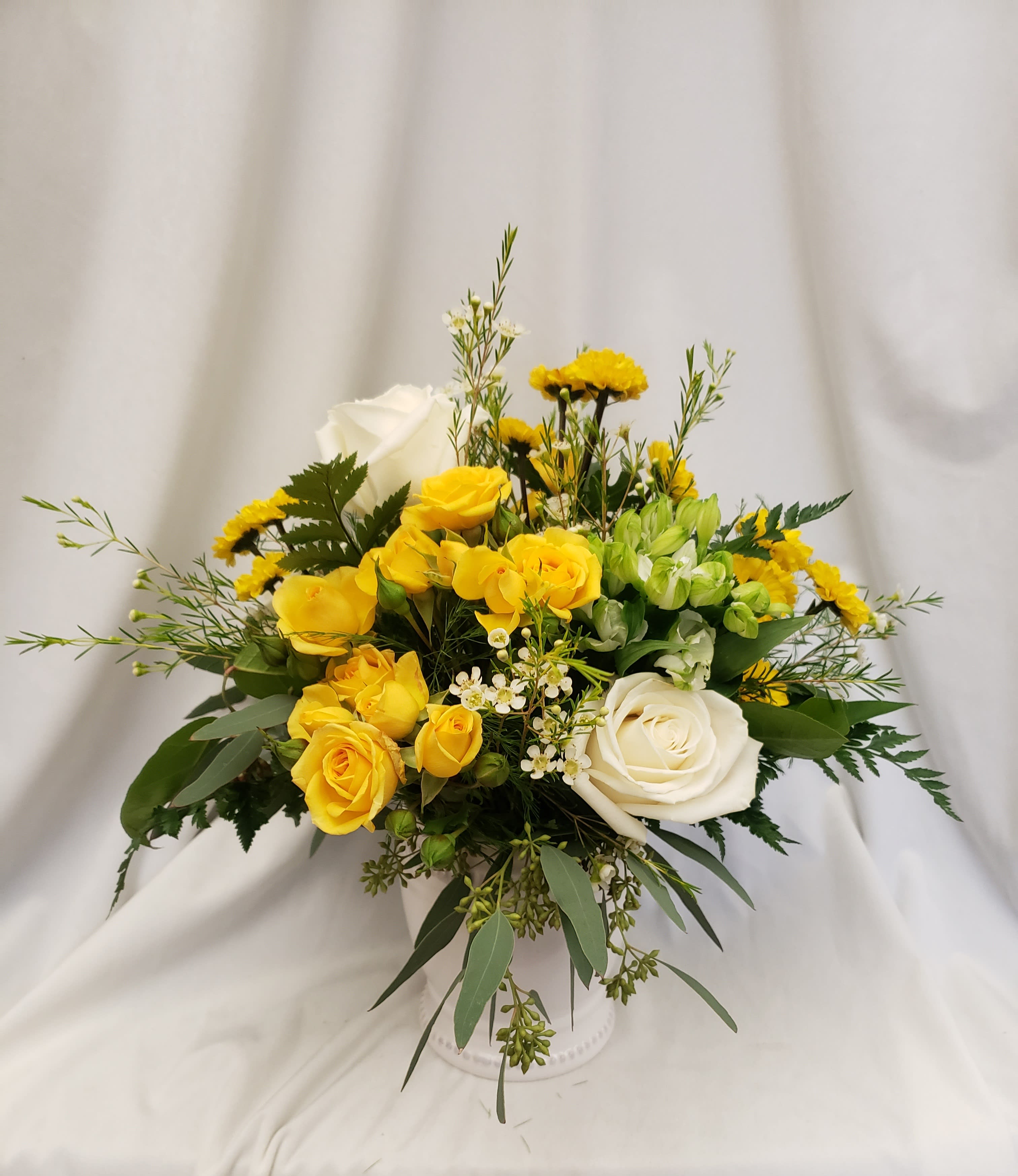 Yellow and white rose arrangement in a white vase