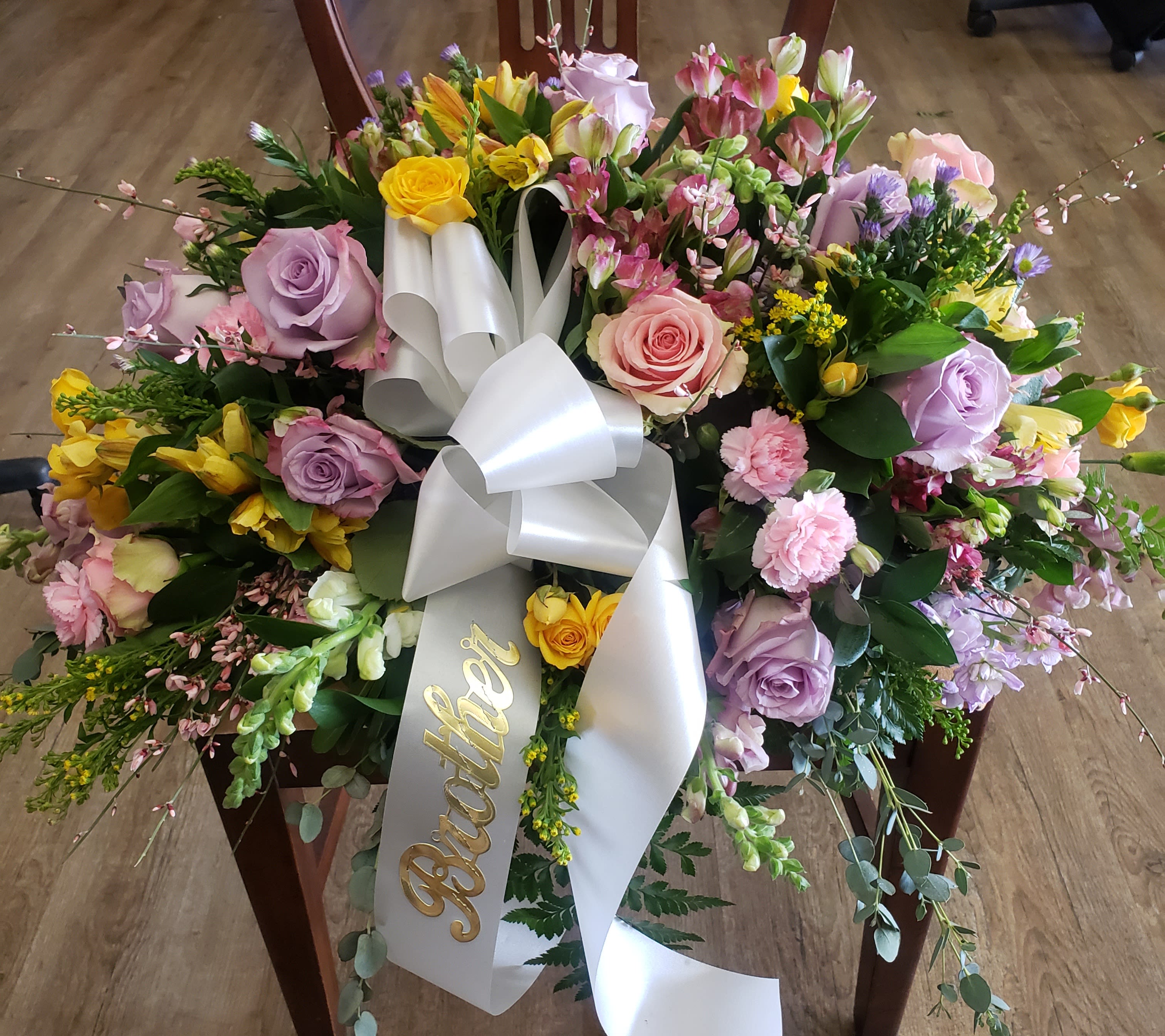 Large floral wreath with pastel roses and a white ribbon bow