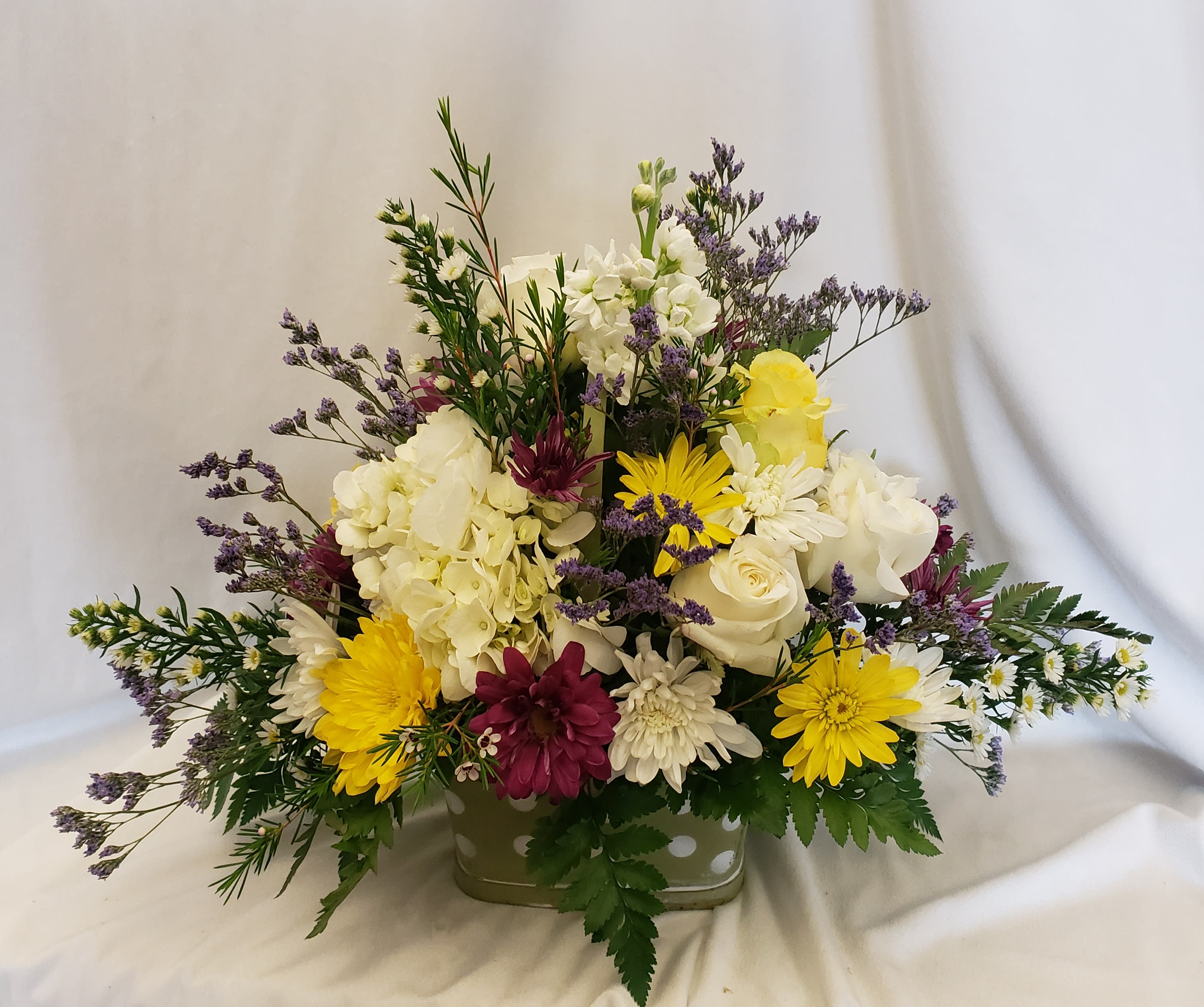 Mixed bouquet in a low rectangular container with white, yellow, and purple flowers