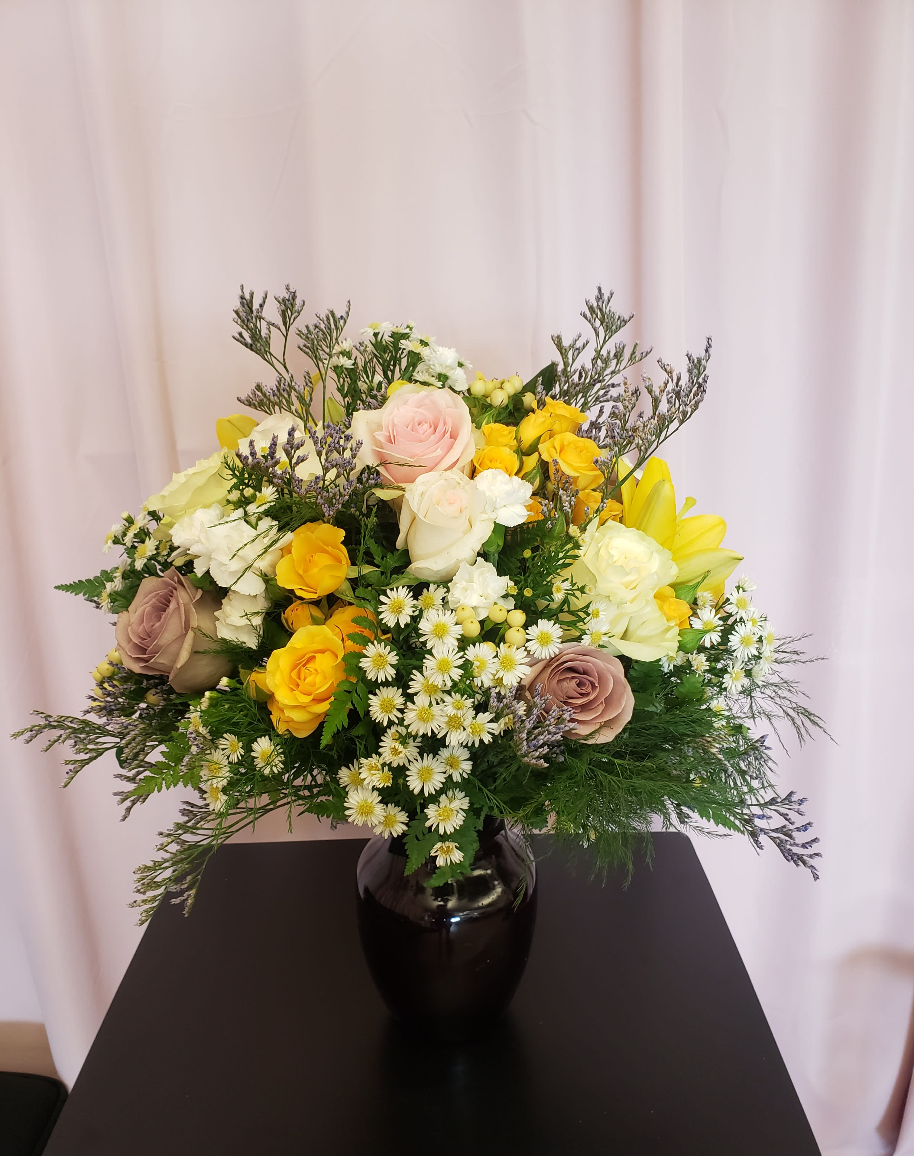 Mixed bouquet of roses and small white daisies in a black vase