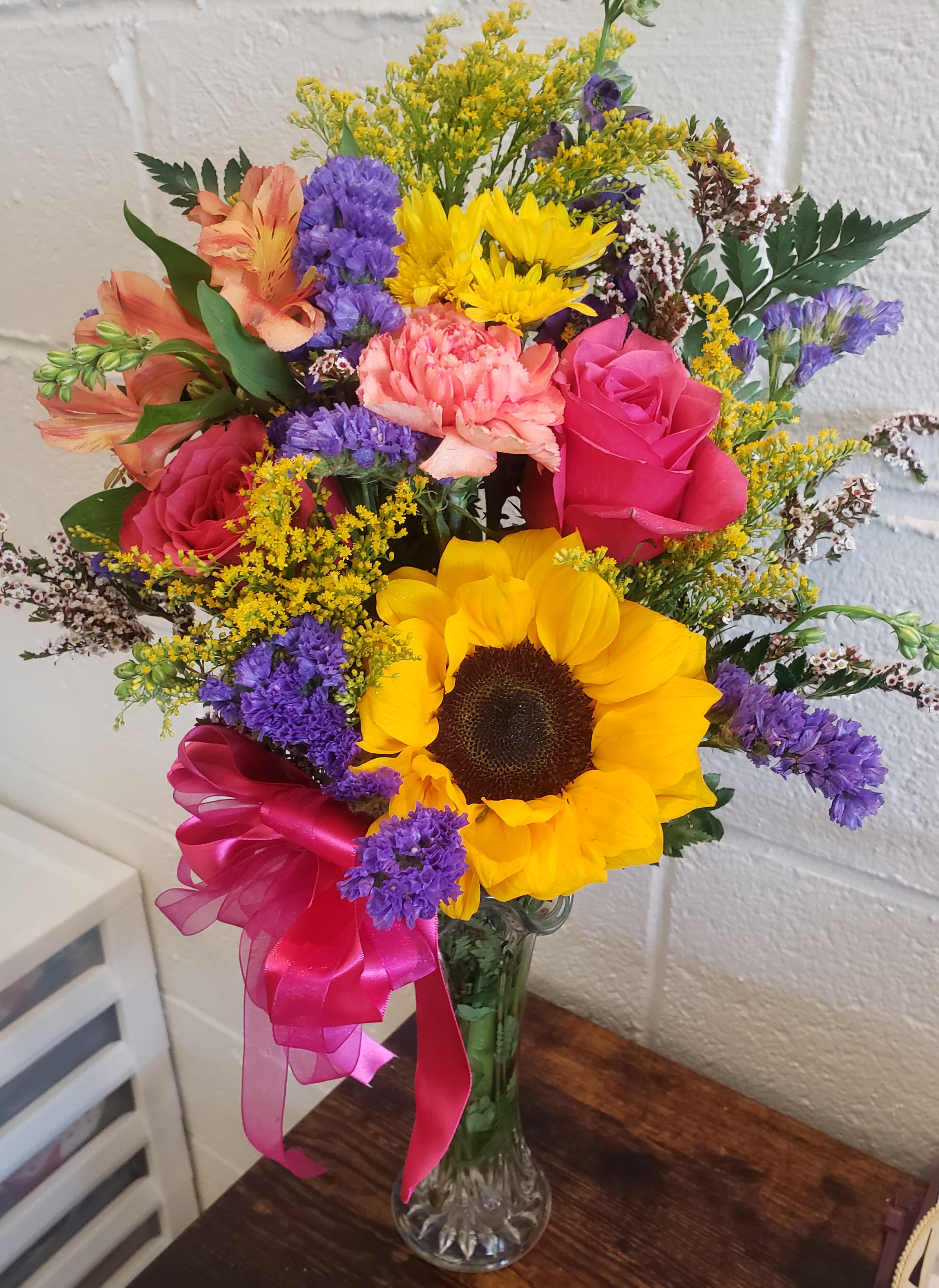 Colorful bouquet with sunflowers, roses, and carnations in a glass vase