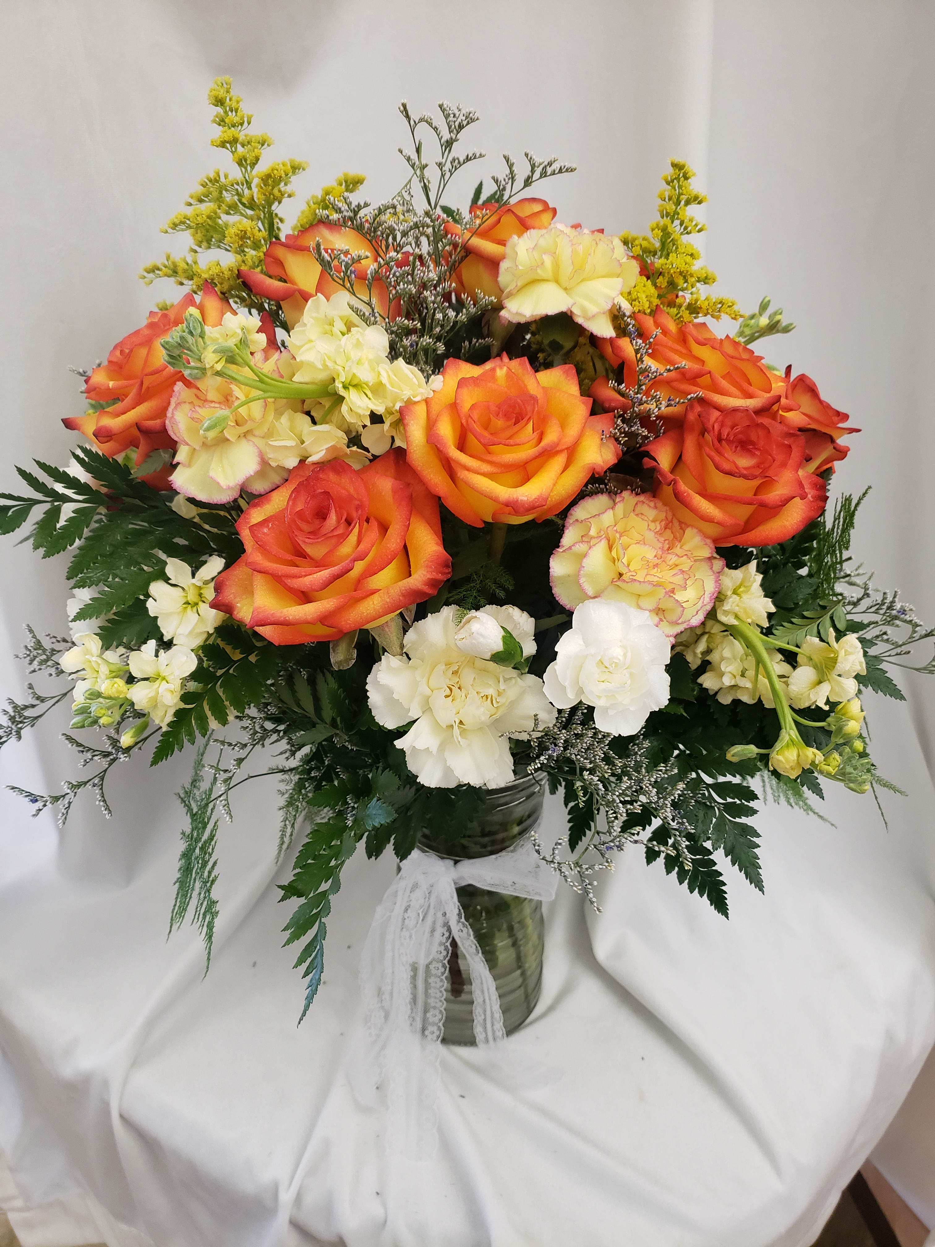 Bouquet of orange roses and pale carnations in a glass vase