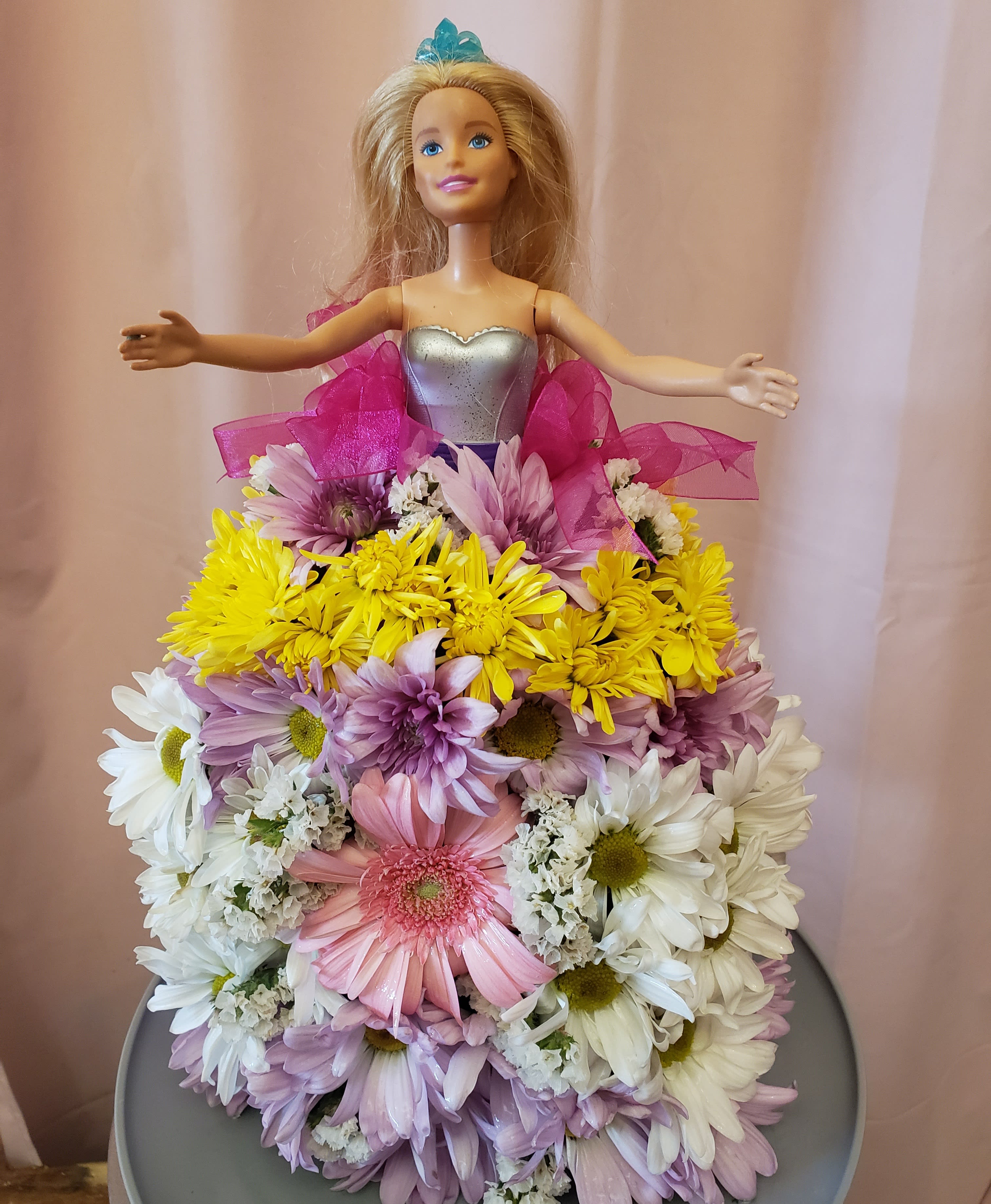 Doll in a dress covered with pastel daisies and ribbon