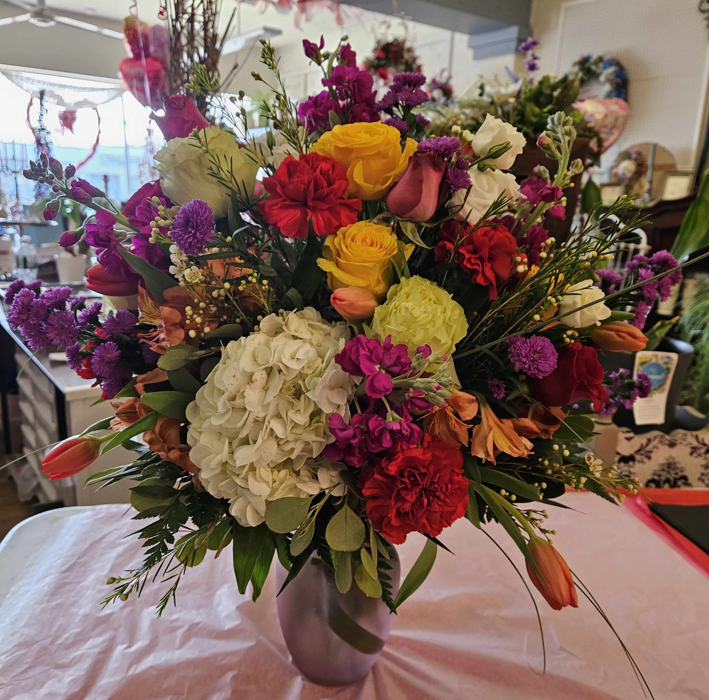 Mixed bouquet of roses, hydrangea, and tulips in a vase