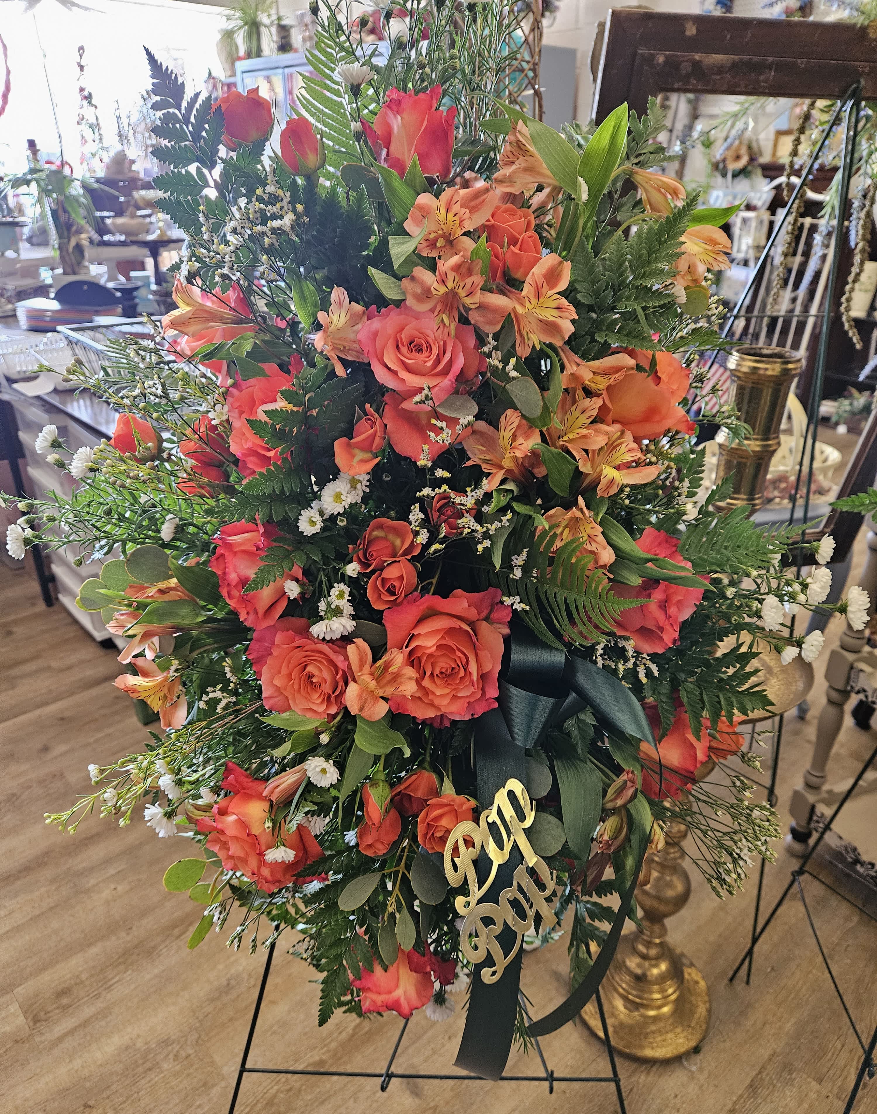 Large standing floral spray with orange roses and alstroemeria on an easel