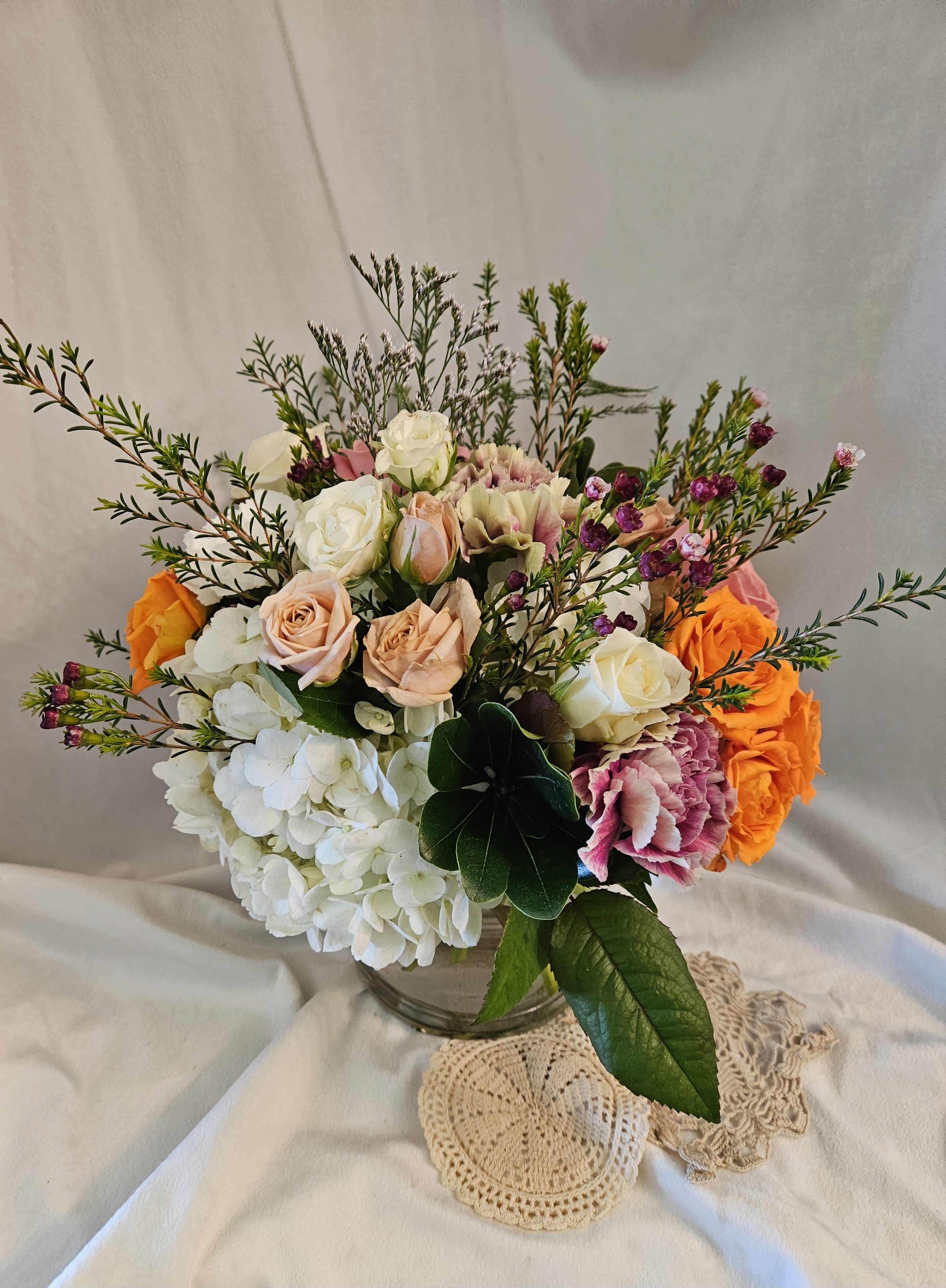 Mixed bouquet of roses, hydrangeas, and carnations in a glass vase