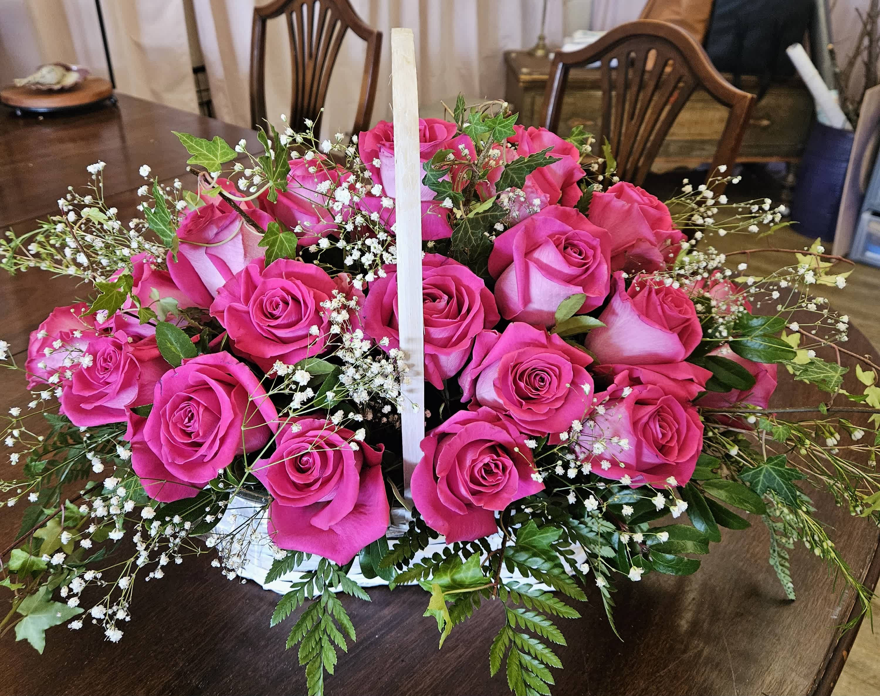 Basket of bright pink roses with baby's breath and greenery