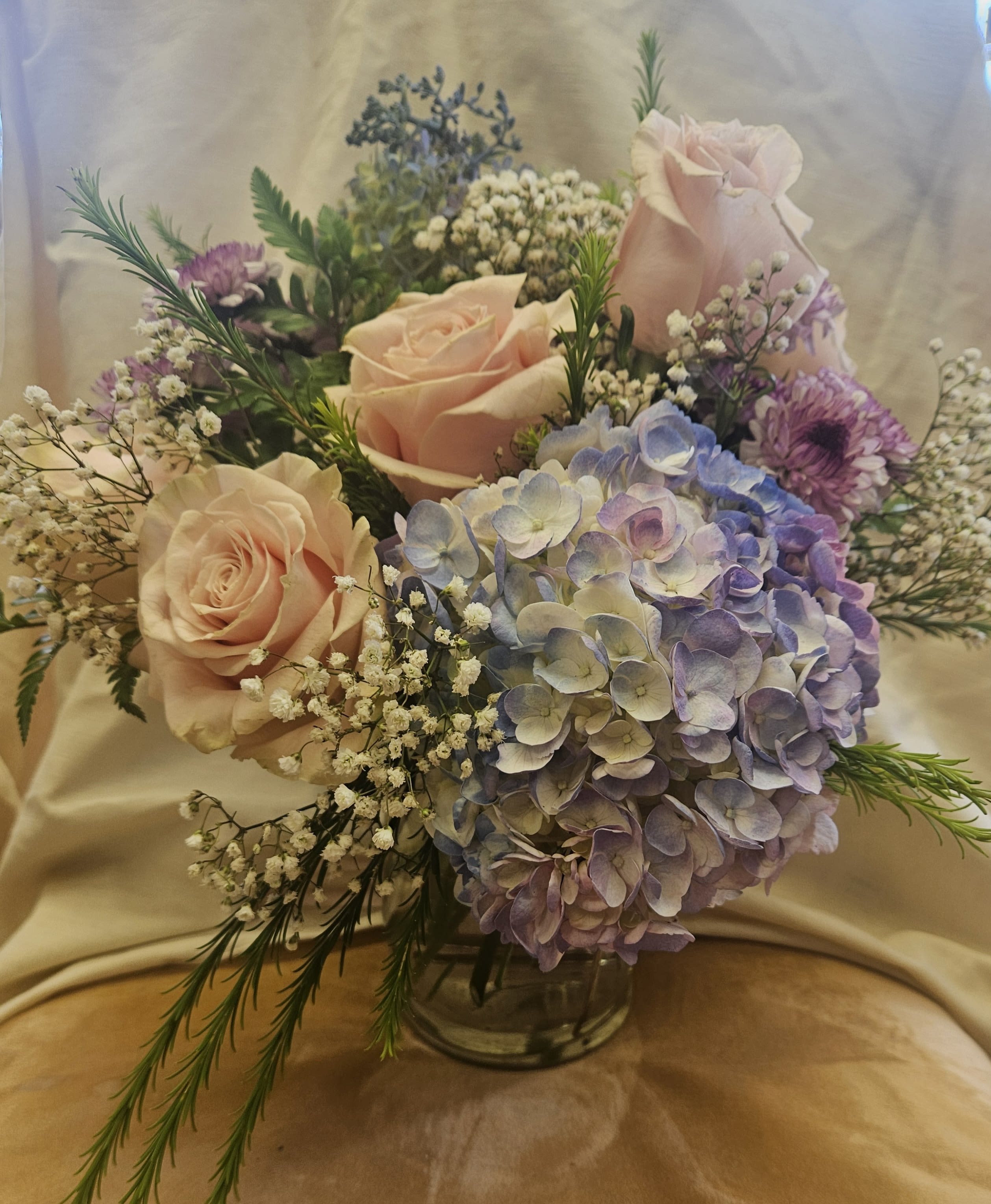 Bouquet of pale pink roses and lavender hydrangea in a glass vase