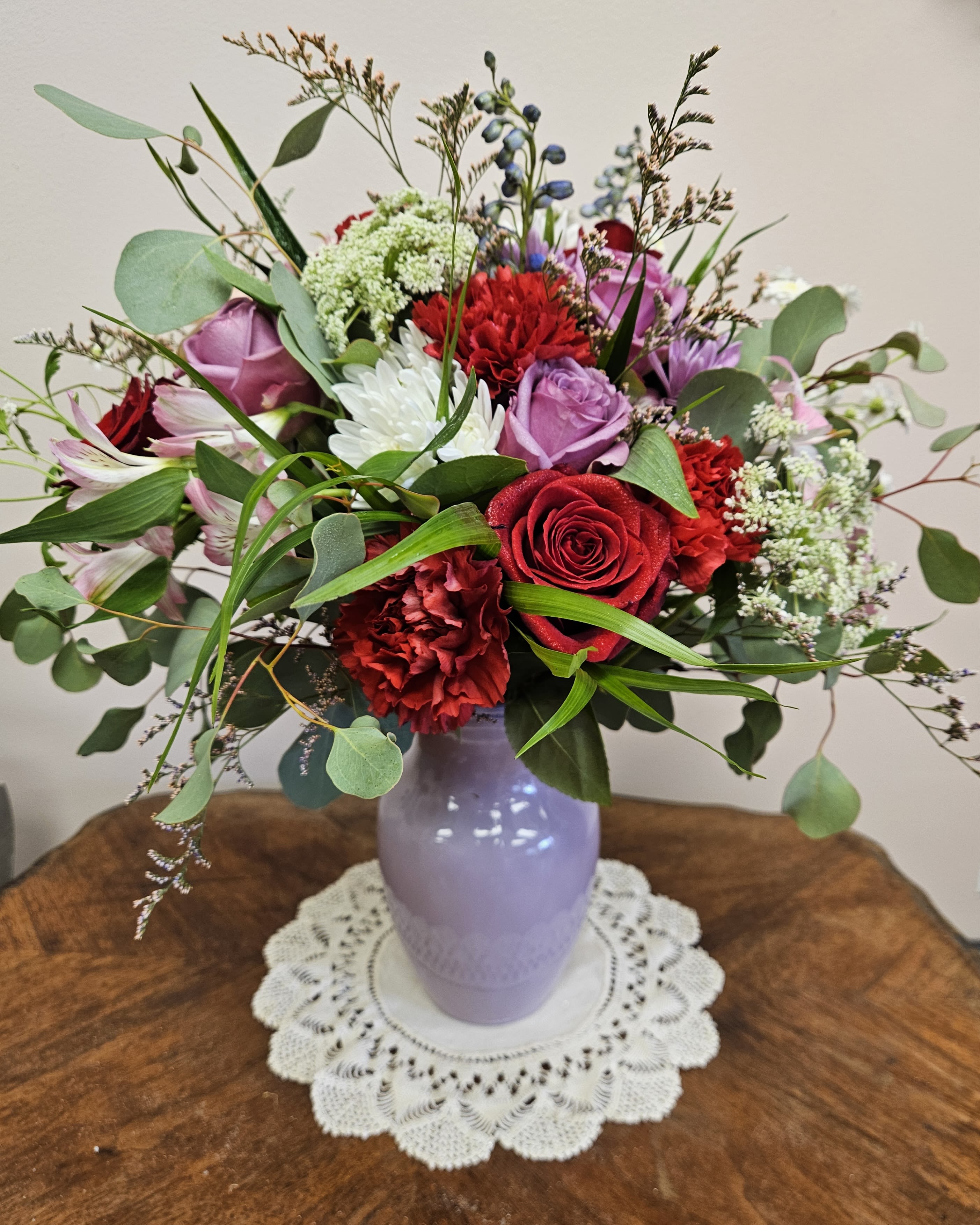 The Mila - Colorful vase arrangement sure to enchant that special someone in your life! Perfect for any occasion. Red carnations, purple, red and light pink roses, feverfew, Queen Anne's Lace, alstroemeria, mums, delphinium and wild eucalyptus. 