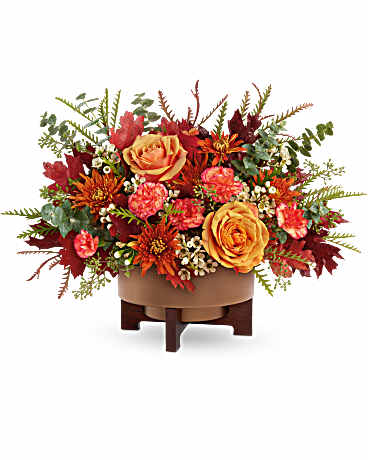 Autumn floral arrangement with orange roses and red blooms in a low container