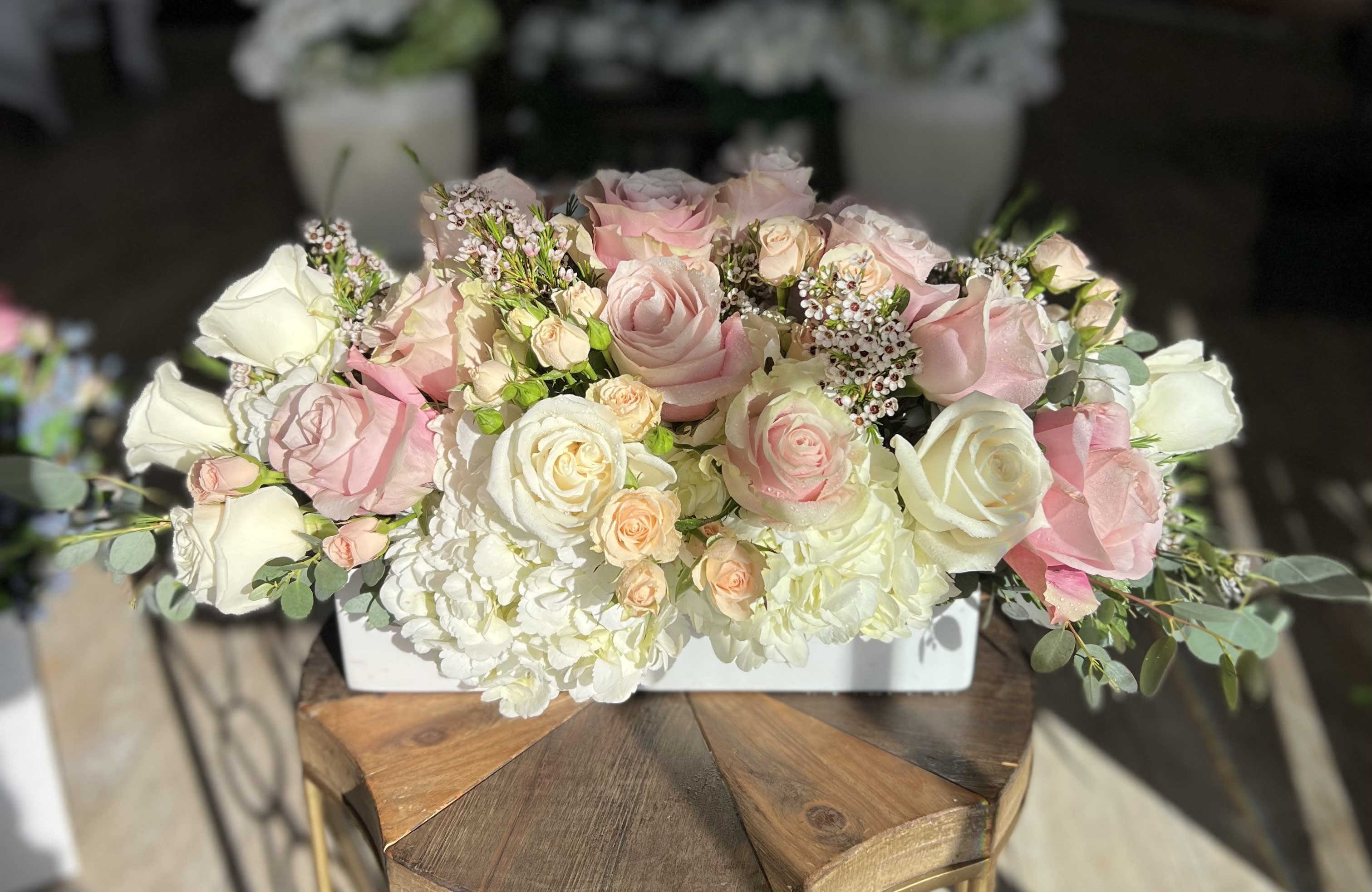 Pink and white roses arranged in a low white container