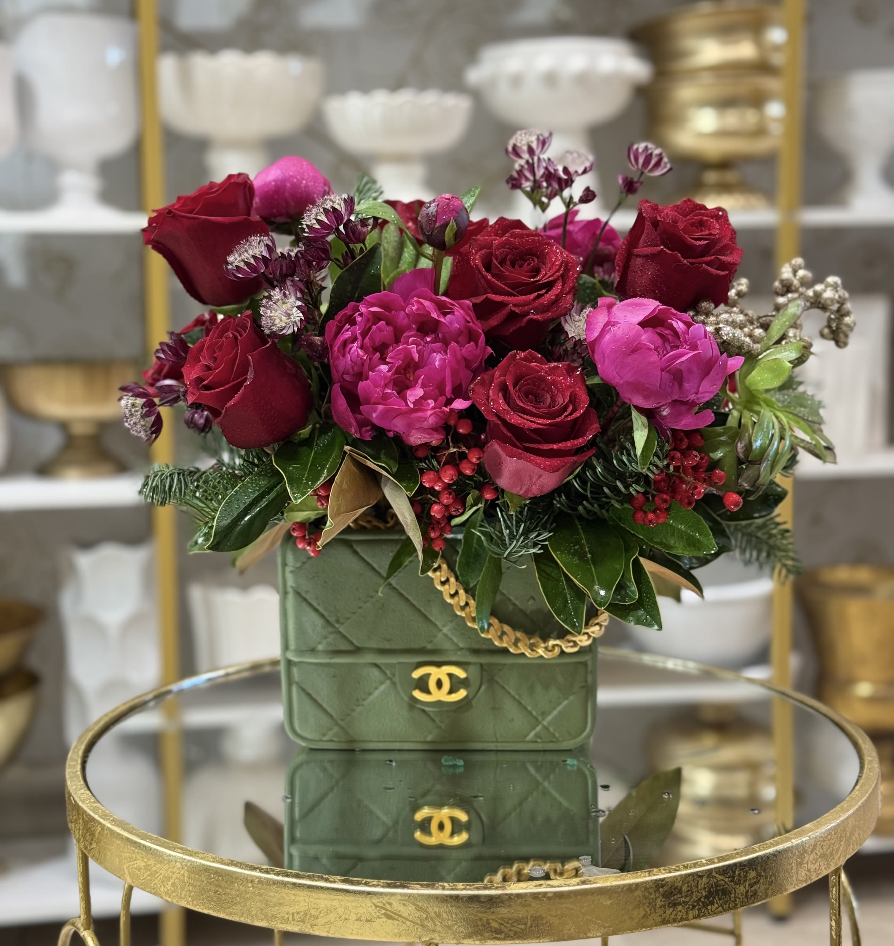 Red and pink rose arrangement in a green quilted handbag-style container