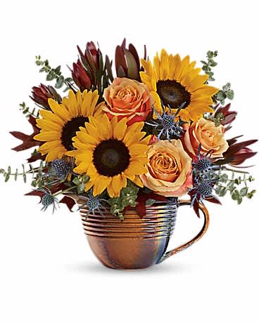 Sunflowers and peach roses arranged in a copper mug