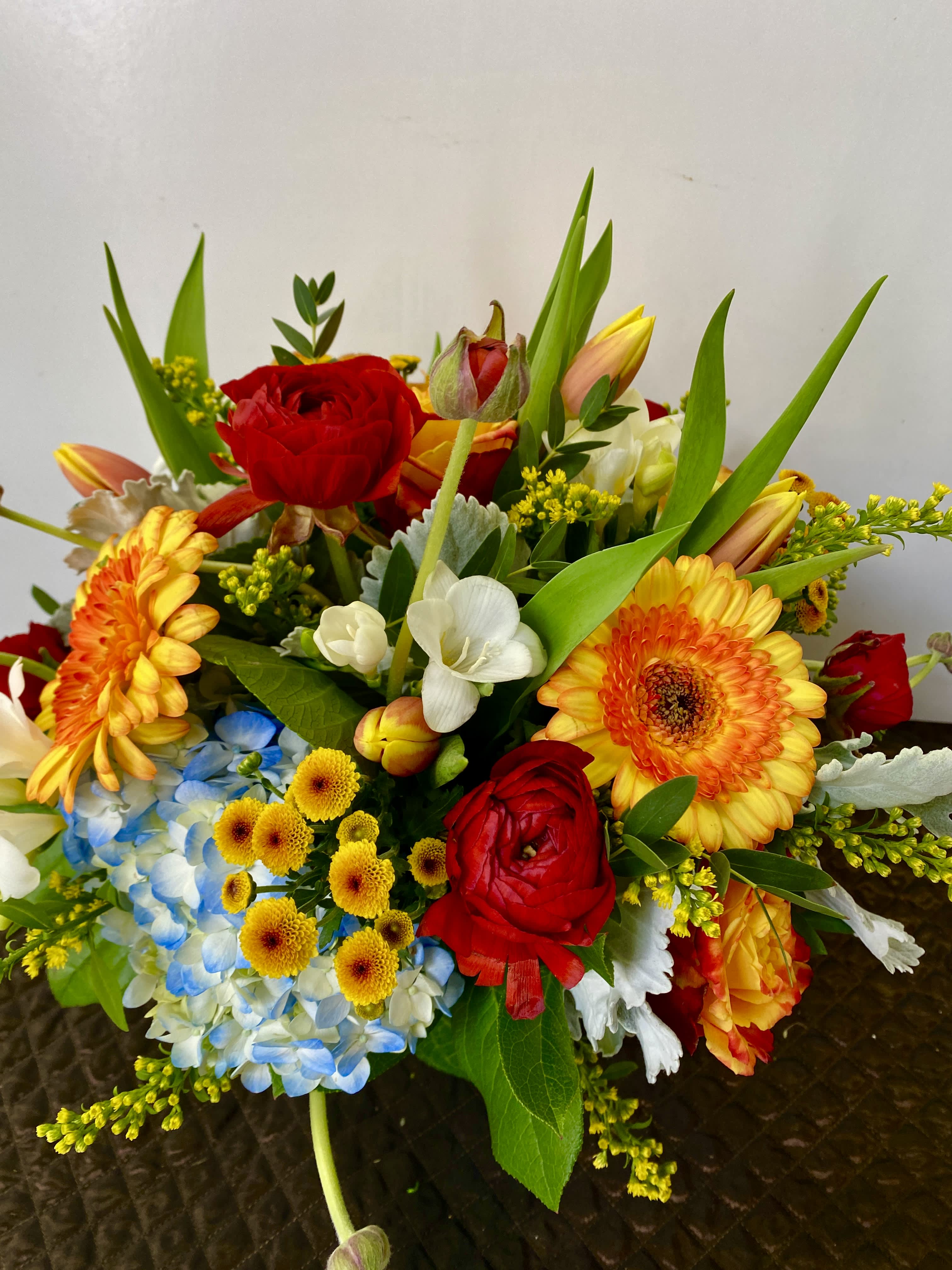 Mixed bouquet with red roses, orange gerbera daisies, and blue hydrangea