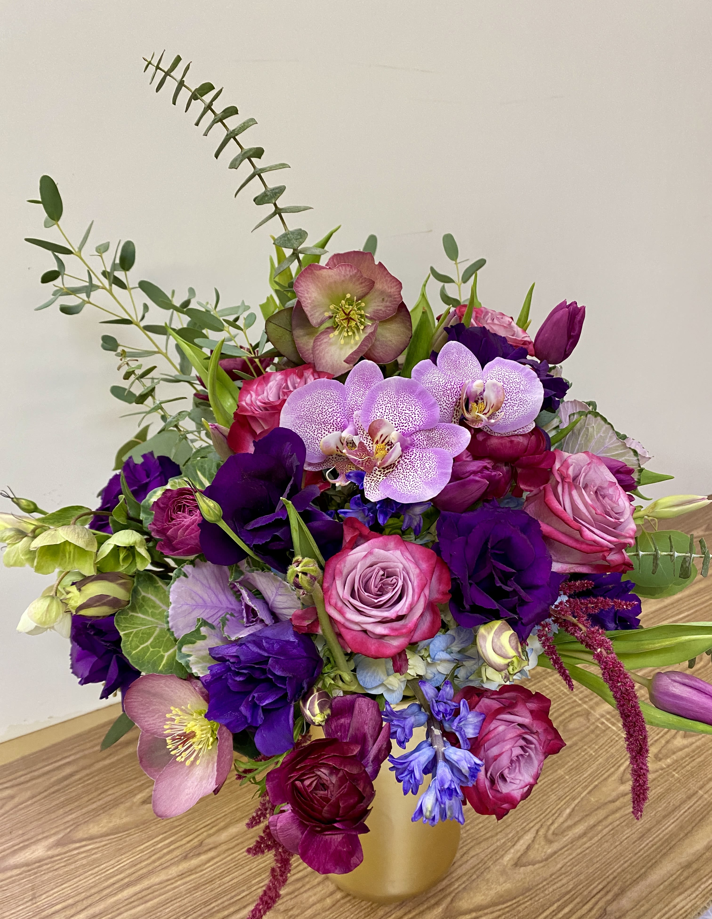 Bouquet of pink, purple, and lavender flowers in a gold vase